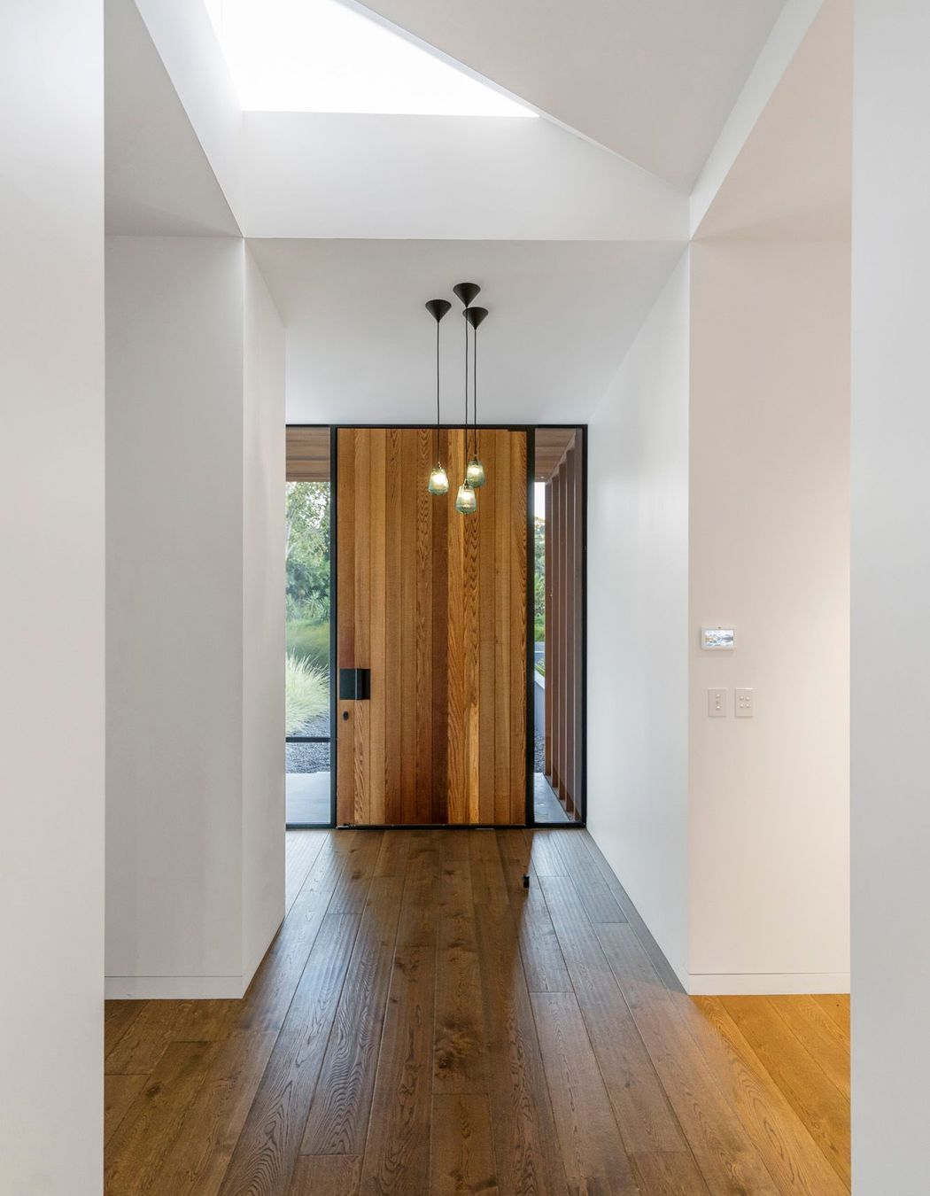  A cedar front door and dark oak flooring are top-lit by a triangular skylight.
