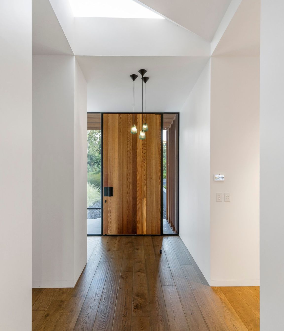  A cedar front door and dark oak flooring are top-lit by a triangular skylight.