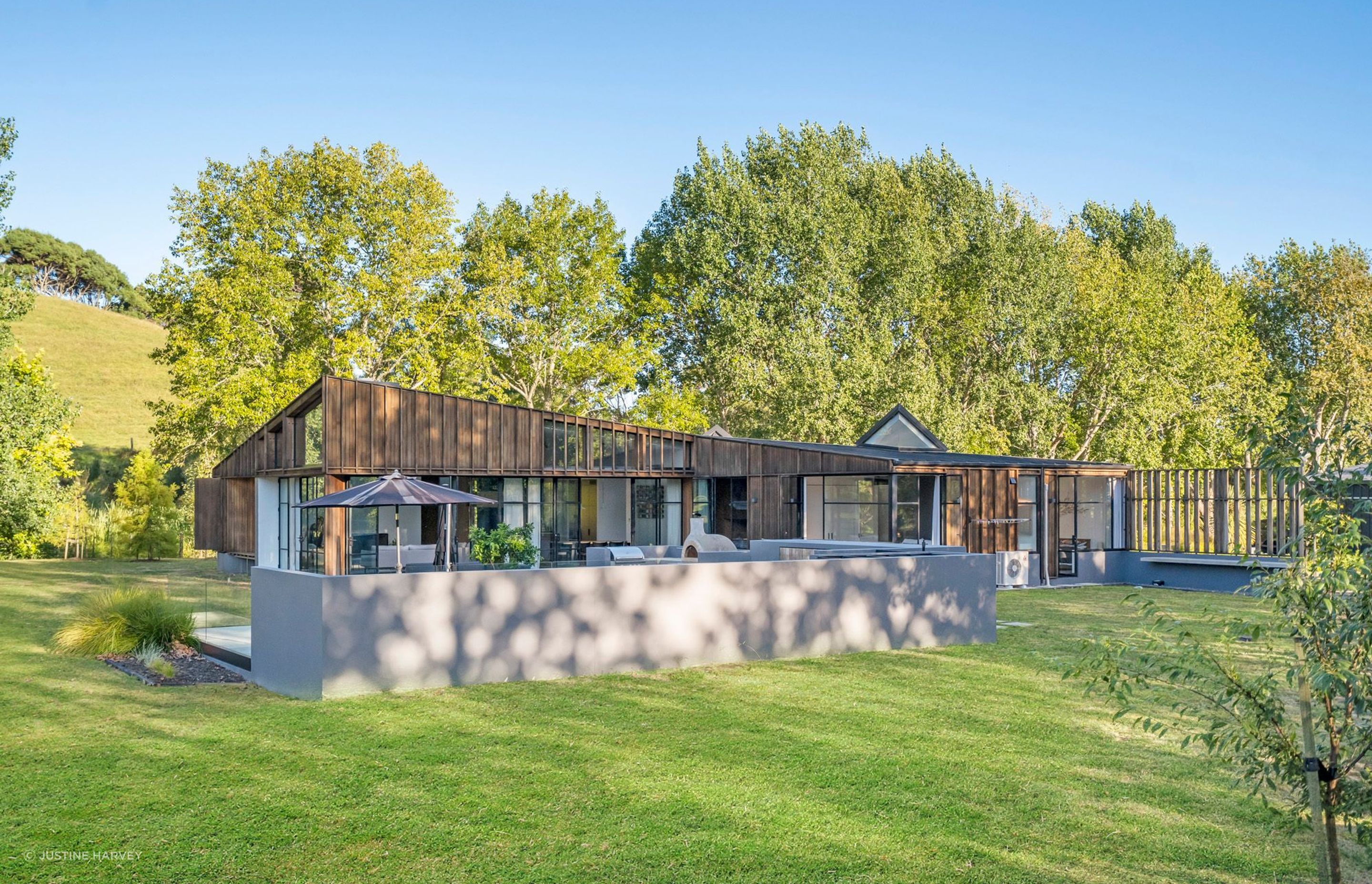 Viewed from the orchard, dappled sunlight floods the swimming pool area at the end of the day. The affectionately named 'bat's ears' or skylights pop out of the top of the roof.