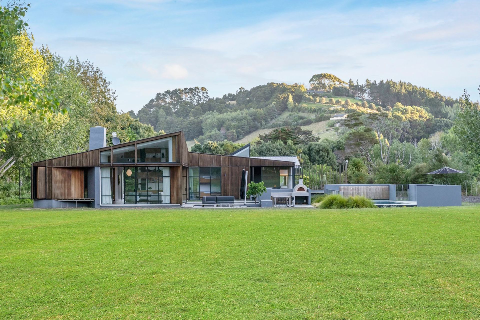 The north-facing elevation features: a large, barn-style window leading into the snug (left); a lounge (middle); the playroom/bunkroom; a bedroom (right) and the courtyard (far right).