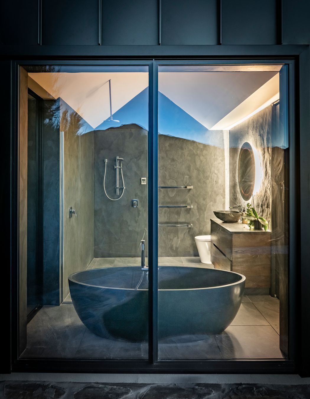 An exterior view of the bathroom with its striking black stone oval-shaped bath.