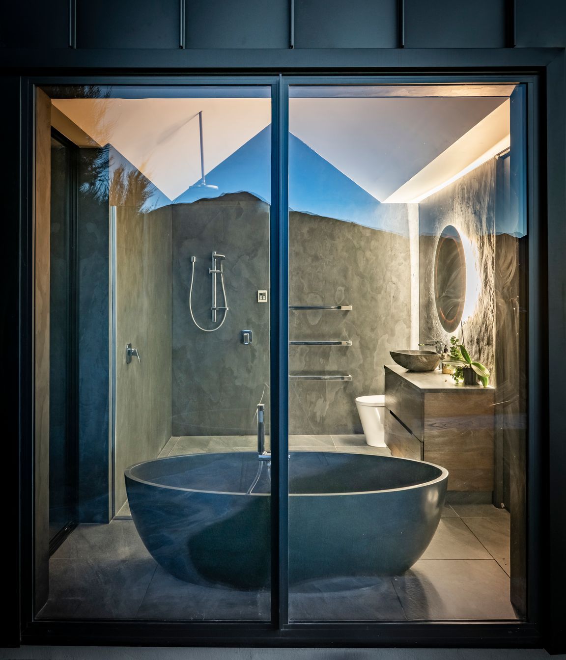 An exterior view of the bathroom with its striking black stone oval-shaped bath.