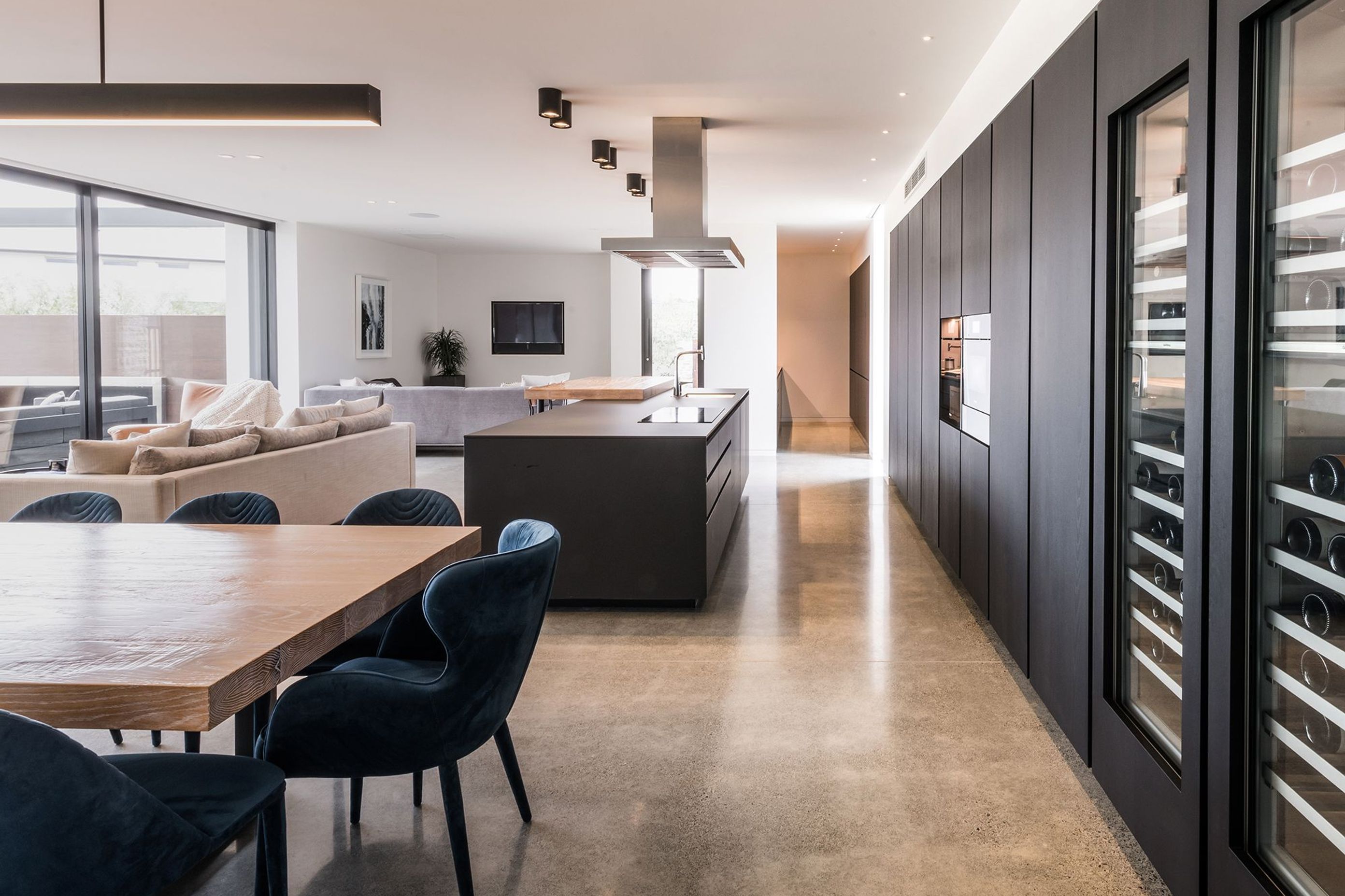 Built-in wine fridges are a feature of the dark timber-veneer cabinetry and provides a strong contrast to the polished concrete floors.
