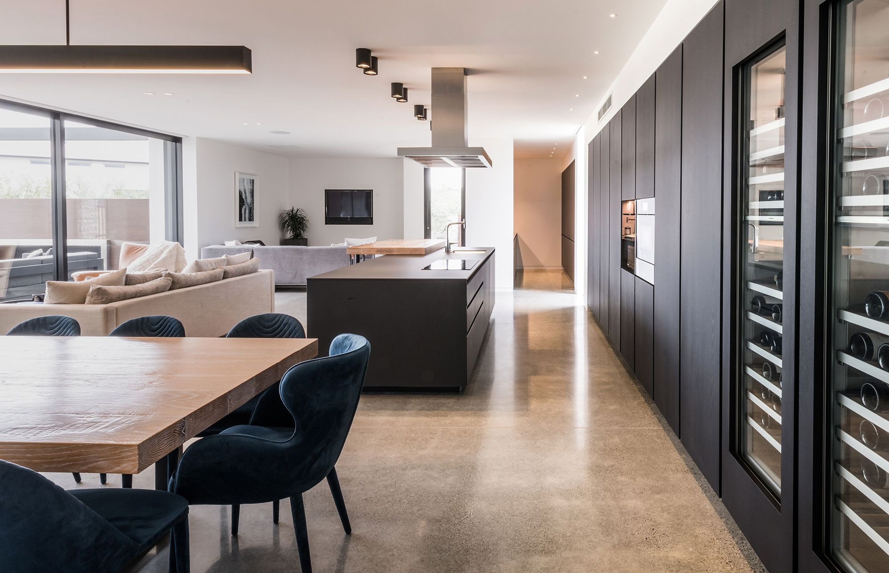 Built-in wine fridges are a feature of the dark timber-veneer cabinetry and provides a strong contrast to the polished concrete floors.