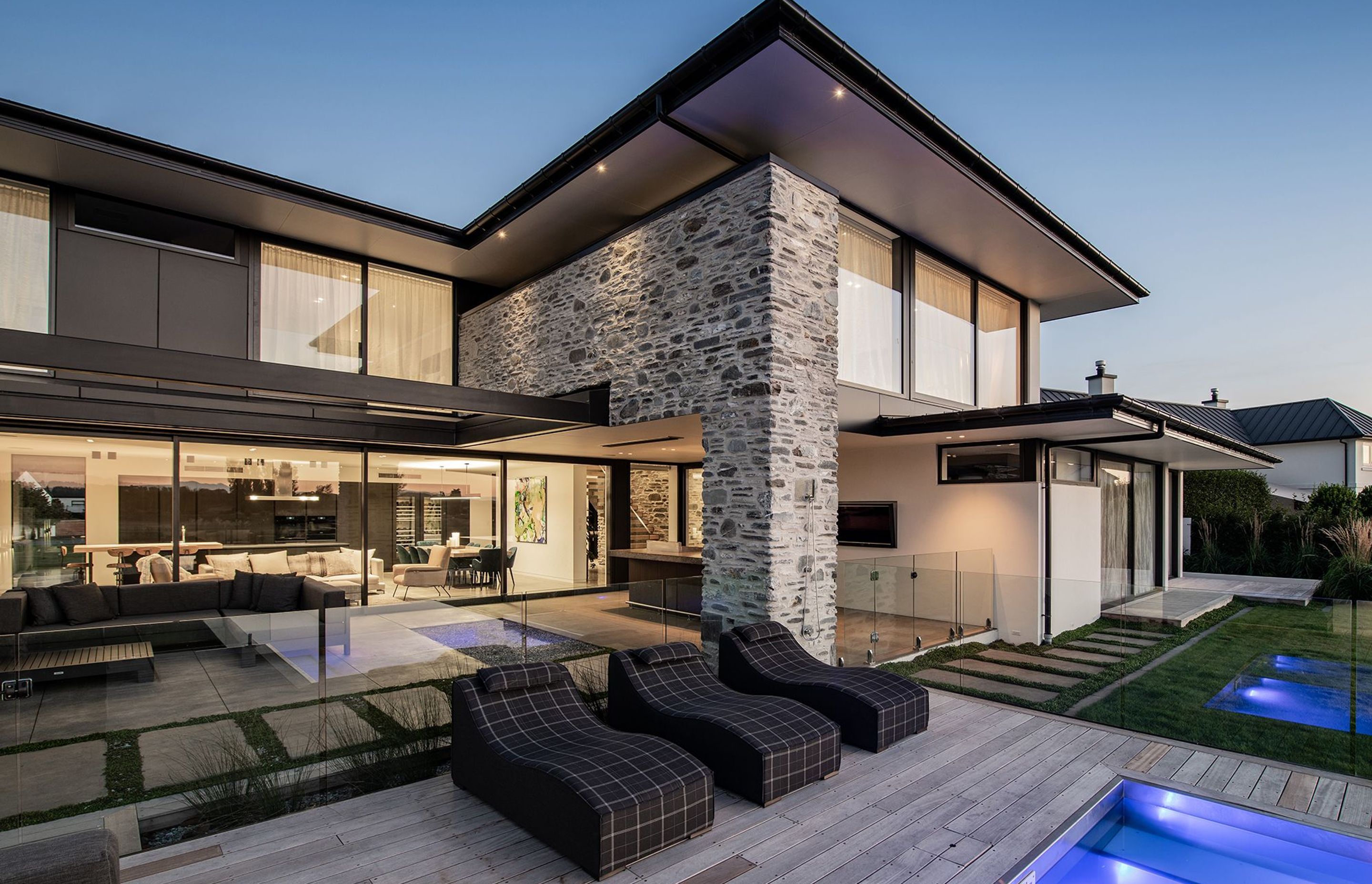 A wall of glazed sliding doors reveals the open-plan kitchen/dining/lounge area inside. A covered teppanyaki bar is nestled under the overhang.