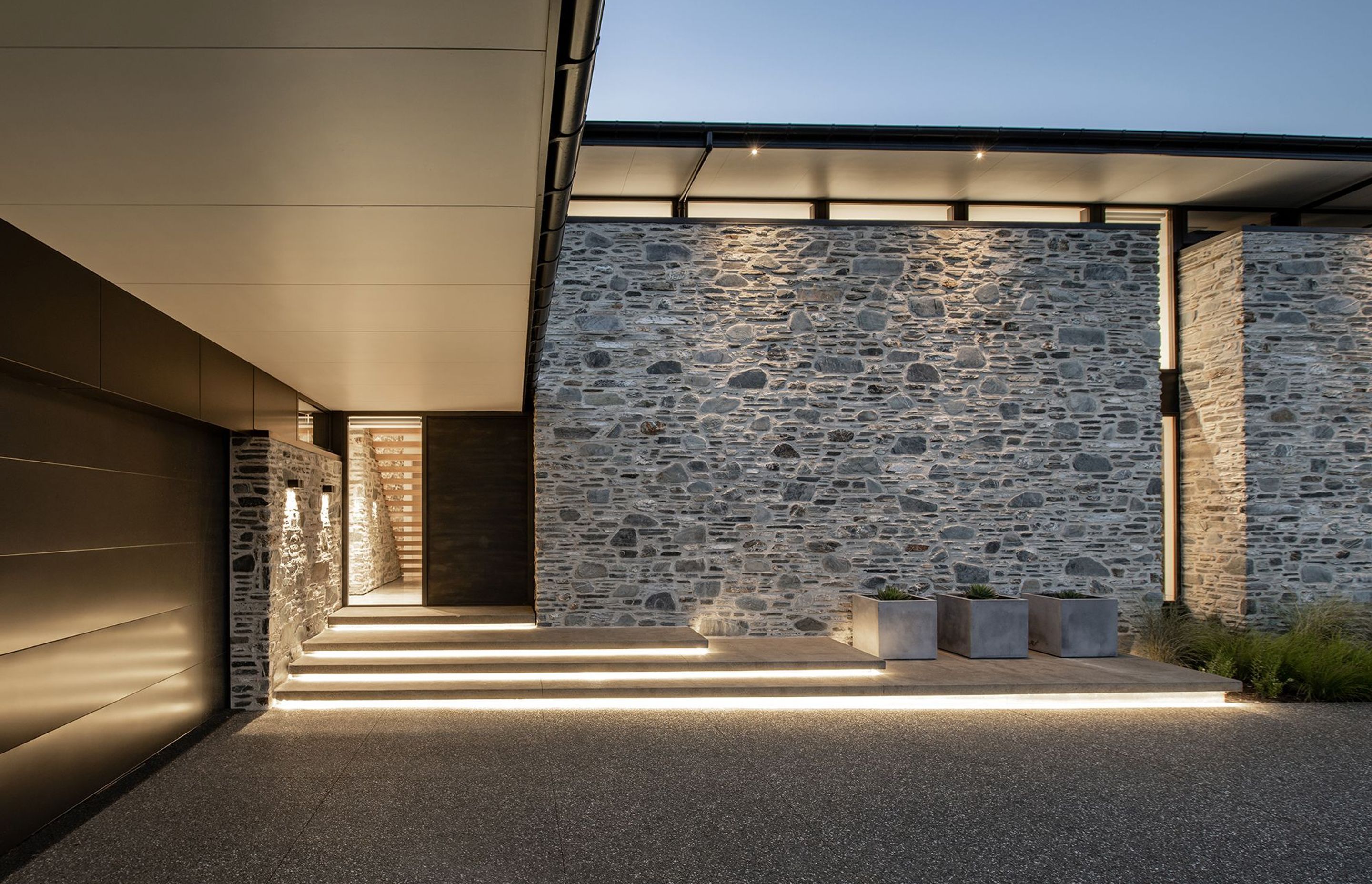 The timber and stone staircase can be seen through the glazed element of the front door. Under-lit steps add drama to the entrance.