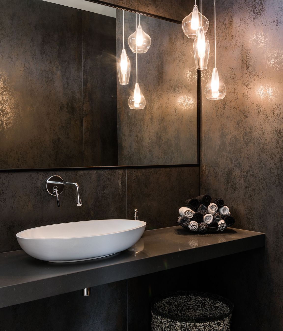 One of the bathrooms features a glass pendant light and metallic-specked tiles.