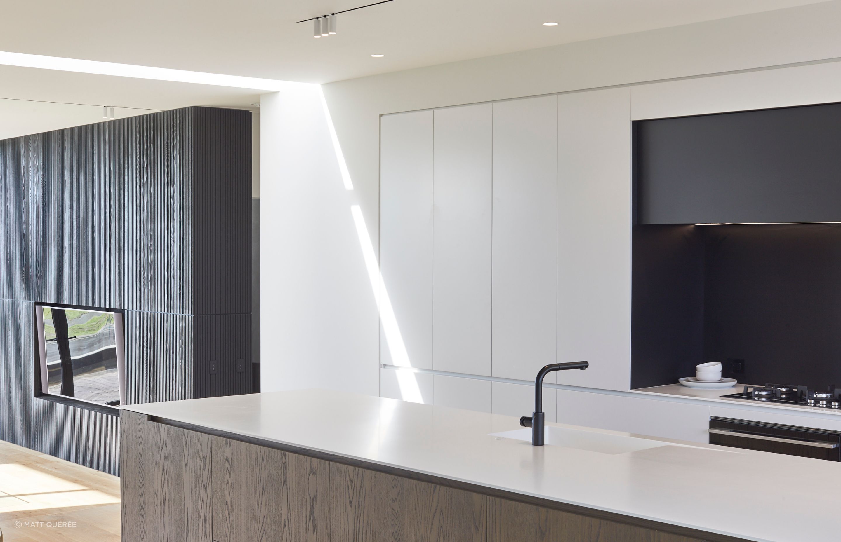 The internal material palette echoes the exterior with timber set against the harder insitu concrete and crisp white walls.