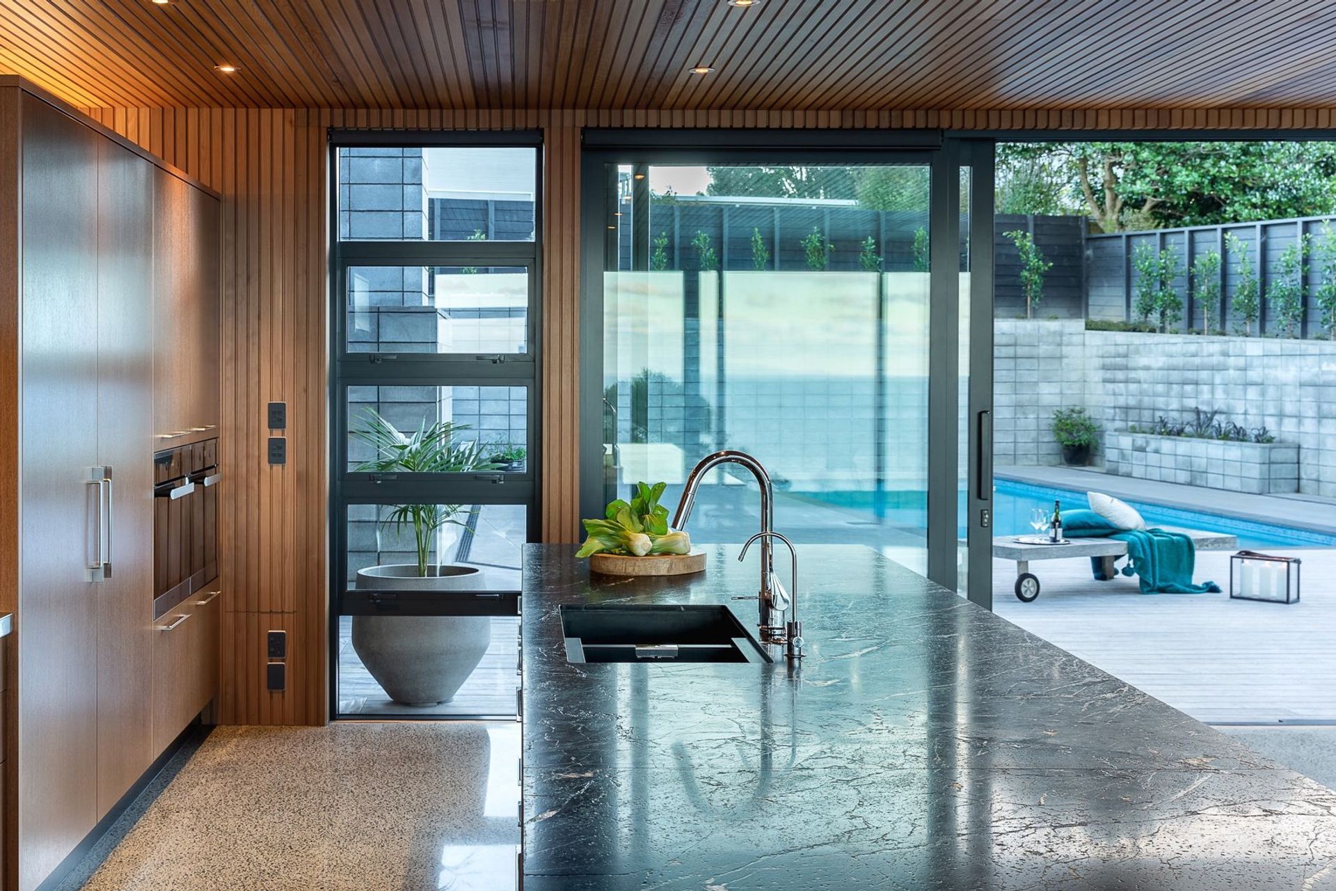 The generous island features a rugged granite bench, chosen for its tactile feel and natural character.  It provides an abundance of set-down space for dishes without interrupting the workflow of the home-chef’s areas,.