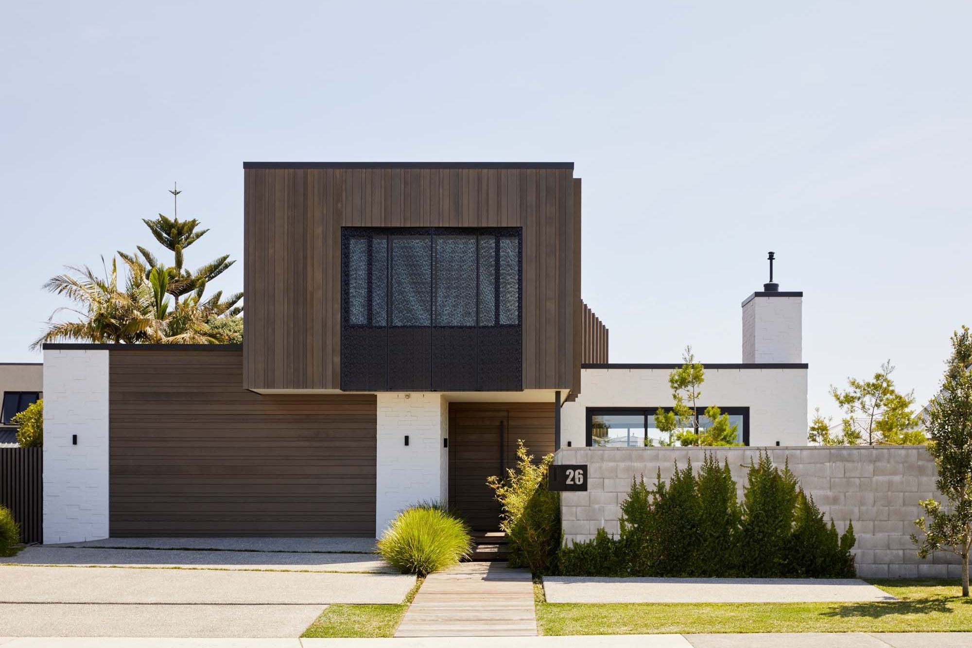 The street elevation has garage and front doors recede into the building, with the upper floor poppiing out out, cantillevered over the front entry, while a blockwork boundary wall will form a green wall once the plants are established,