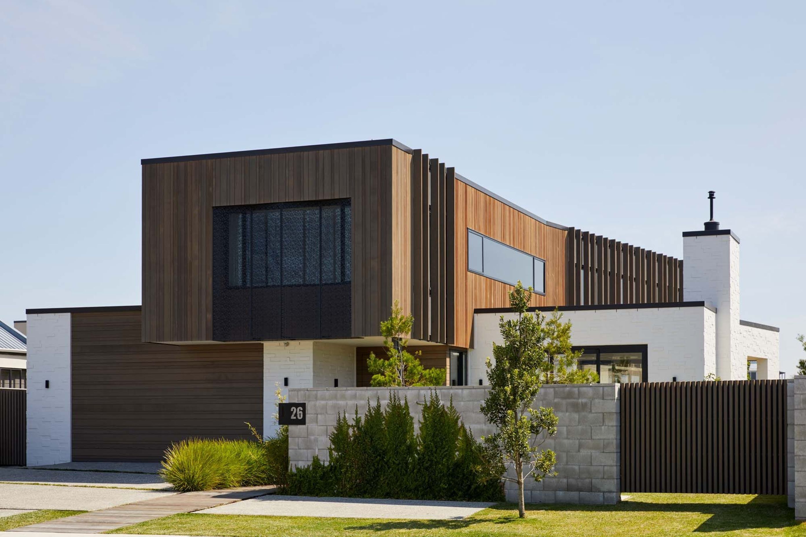 A cedar-clad box perches upon a white bagged brick box, creating a dynamic form that appears narrow from the street and runs along the length of the site towards the park.