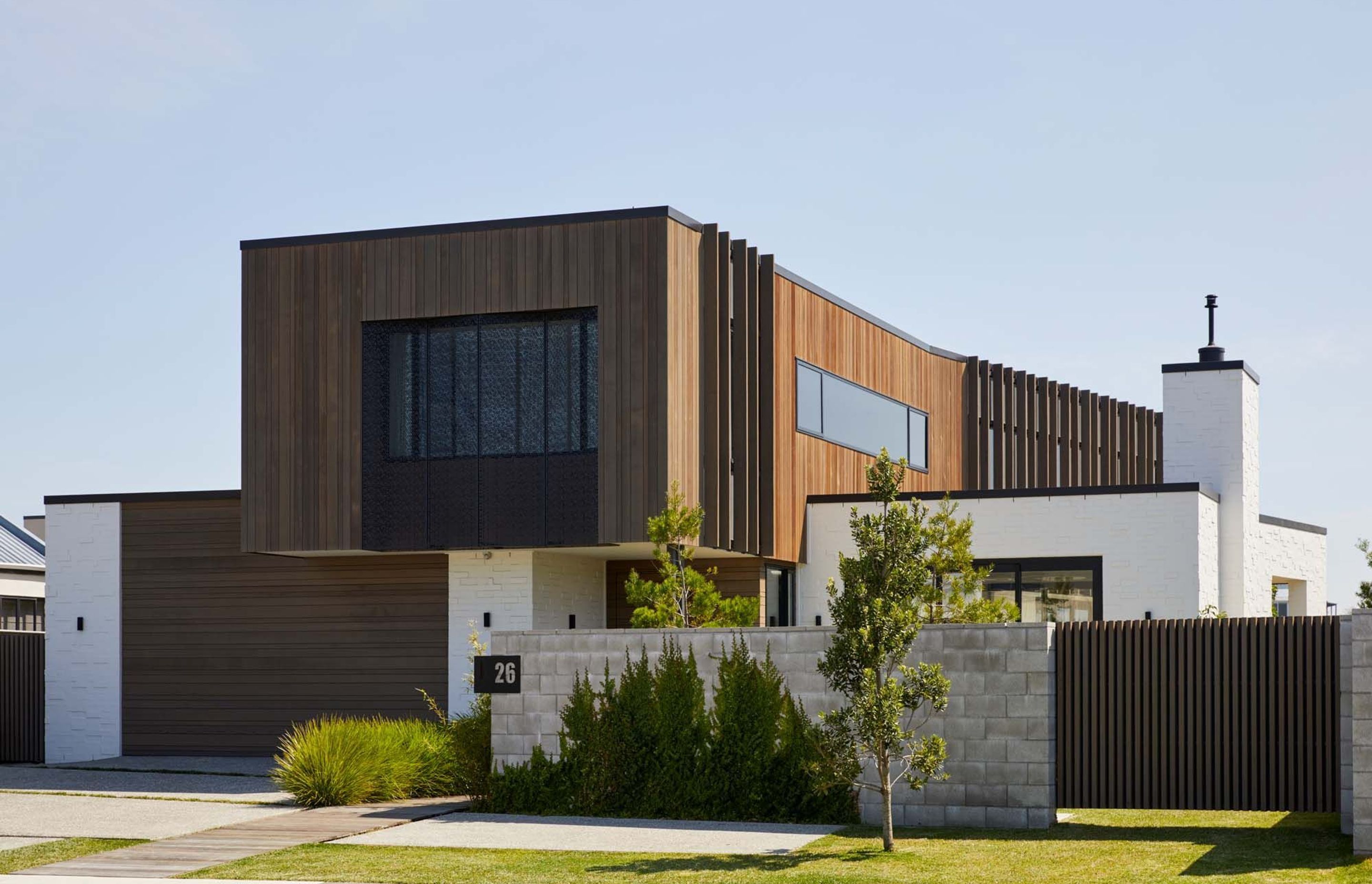 A cedar-clad box perches upon a white bagged brick box, creating a dynamic form that appears narrow from the street and runs along the length of the site towards the park.