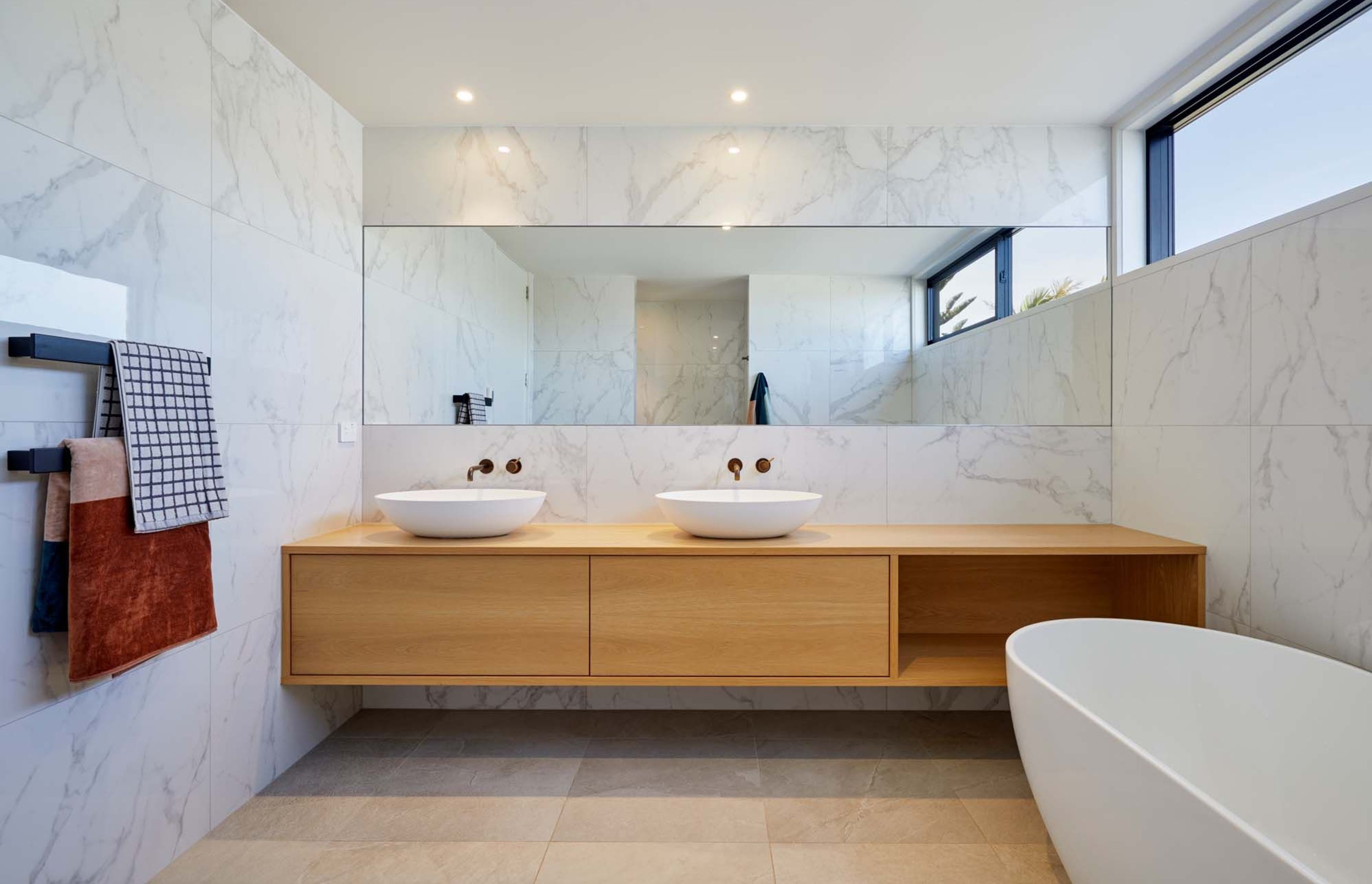 Large format marblesque tiles and bespoke timber cabinetry add a sense of luxury to the bathroom.