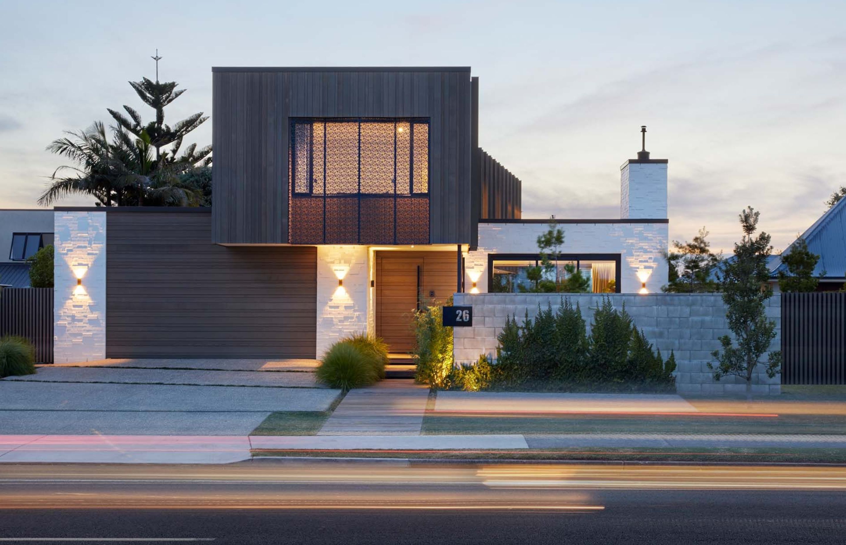 The street elevation seen at dusk shows how the house is beautifully lit to emphasise the textural material qualities of the cladding and the screening.