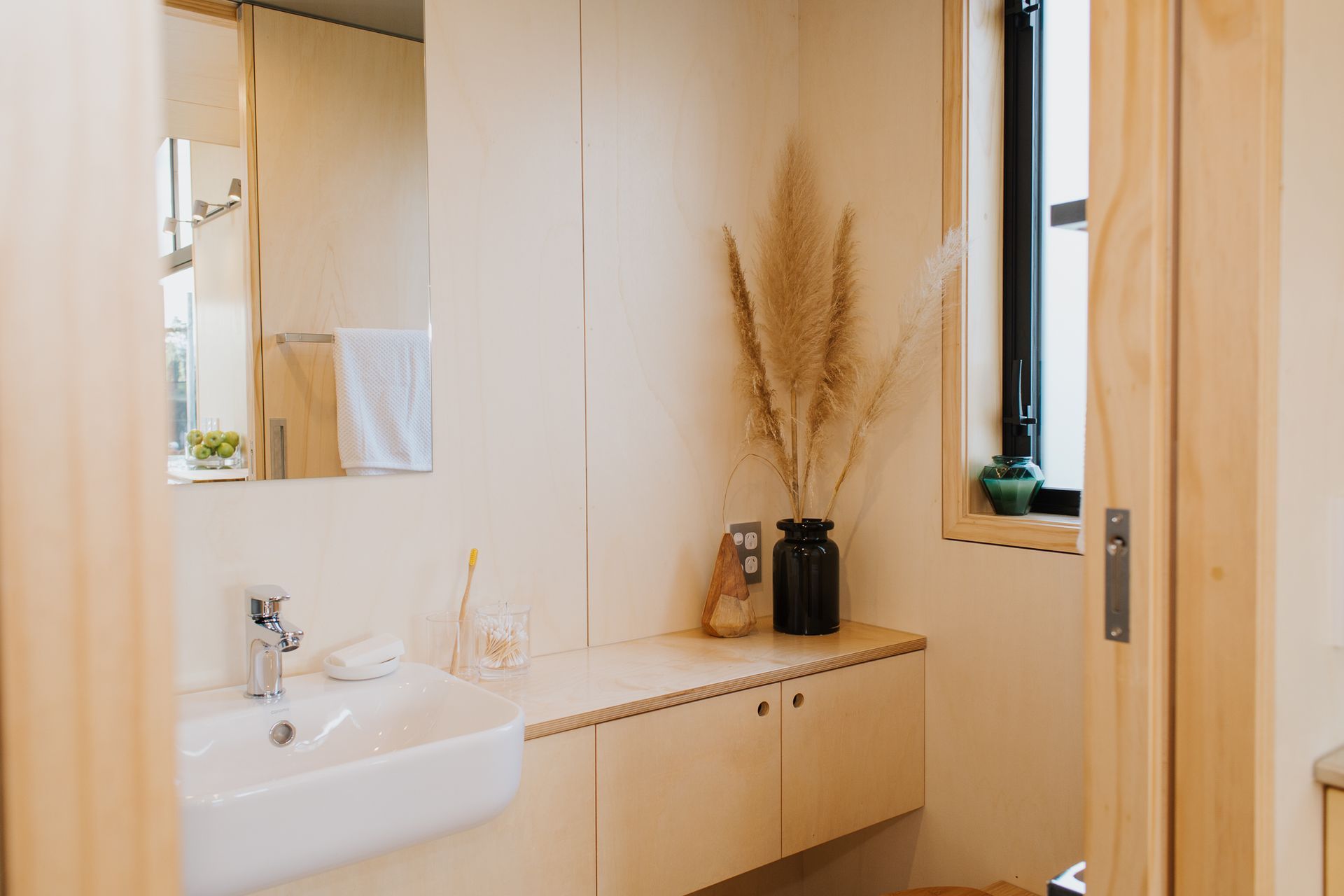 The bathroom features a cavilty sliding door, built-in plywood storage and a bamboo composting toilet. Photography supplied by Build Tiny.