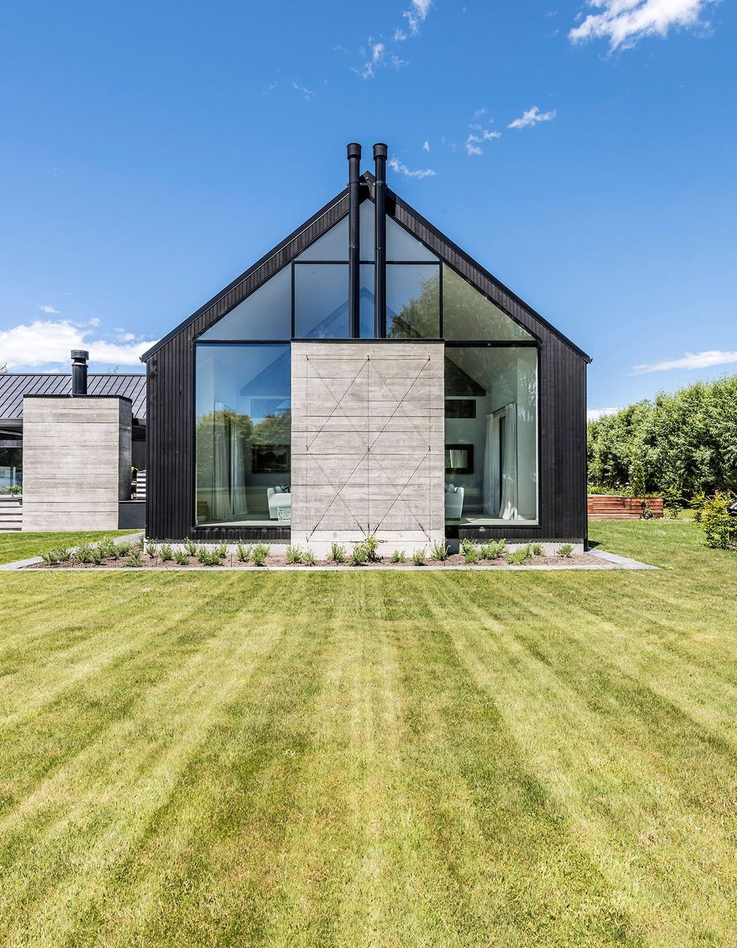 A cast-concrete fireplace sits centre-stage within a glazed gable end.