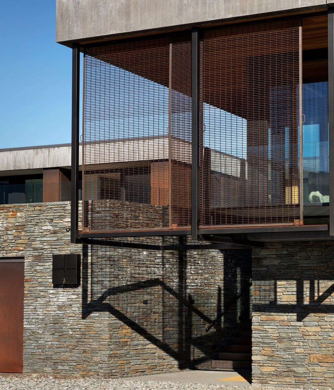 Rusty steel caging and schist stone take inspiration from buildings fo the region.