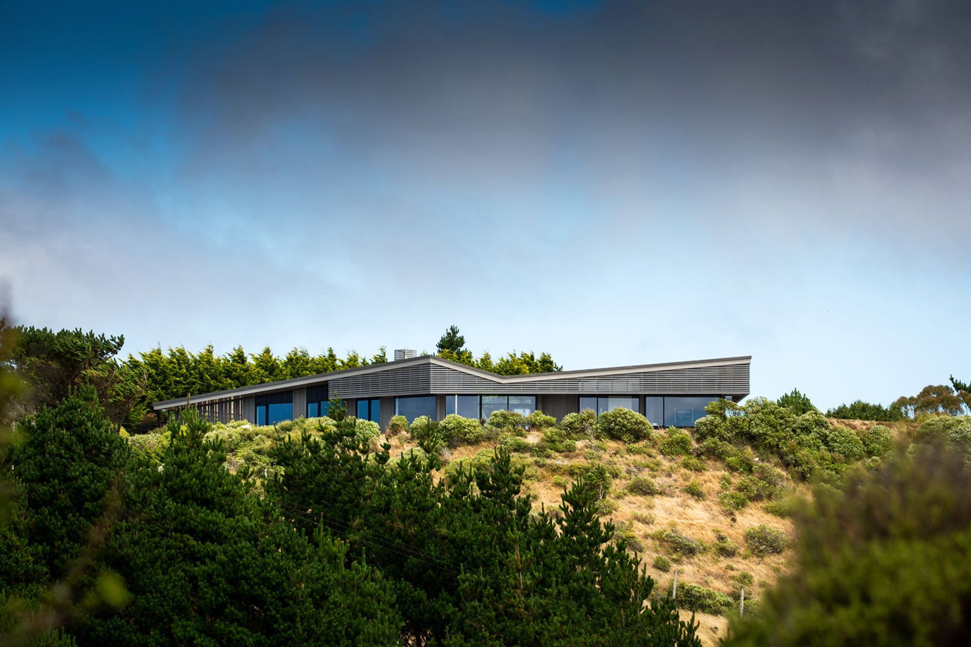 The house utilises timber slatting as a sieve to reduce the serious winds that blow in from the north/north-west. It's form helps to steer the wind away from the house. 