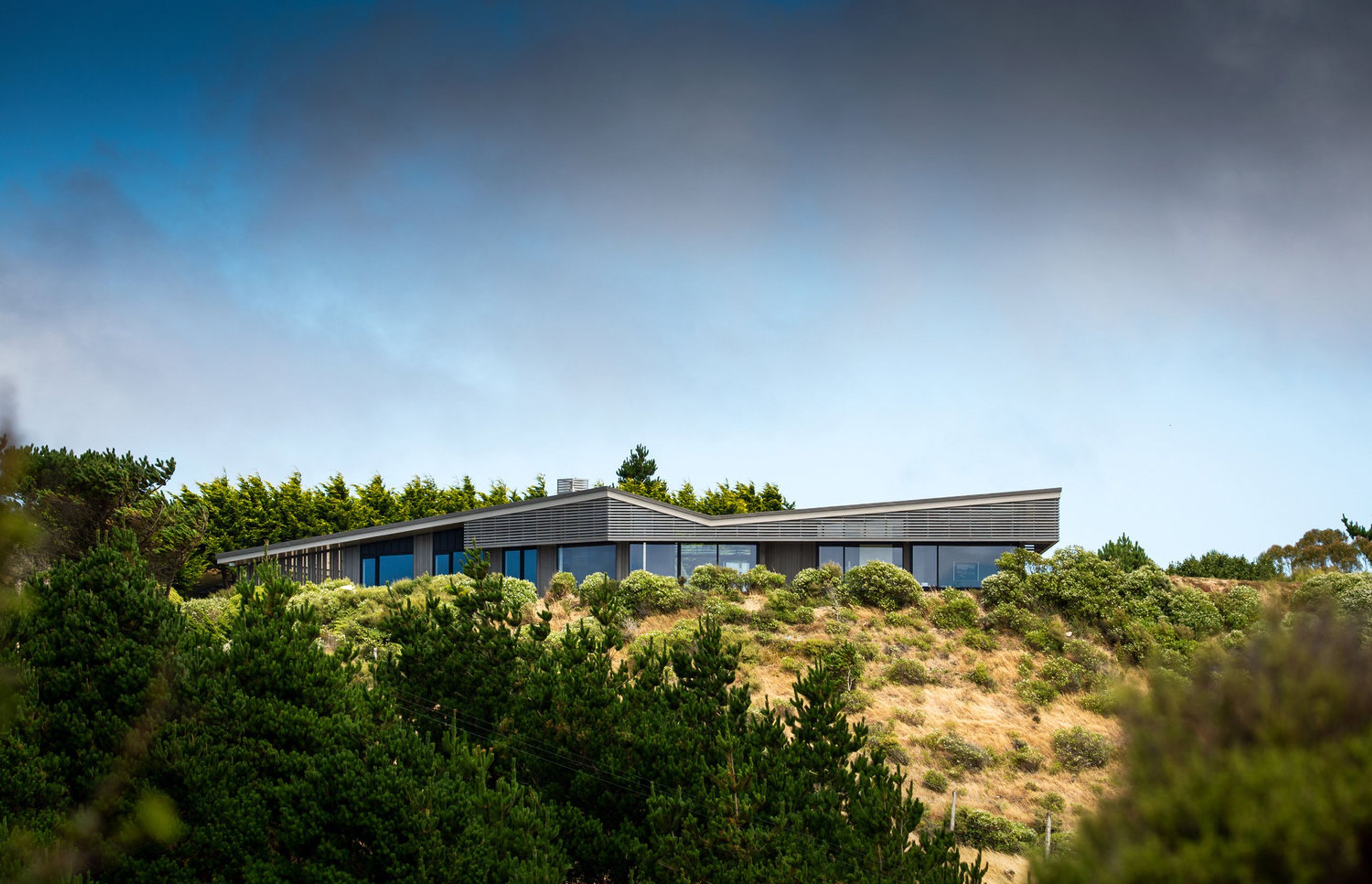 The house utilises timber slatting as a sieve to reduce the serious winds that blow in from the north/north-west. It's form helps to steer the wind away from the house. 