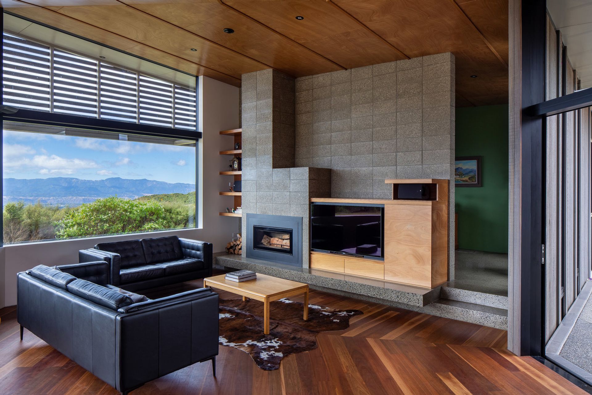 The living area incorporates Parsonson Architects' signature bespoke cabinetry. A pops of green wall indicates the study in behind.