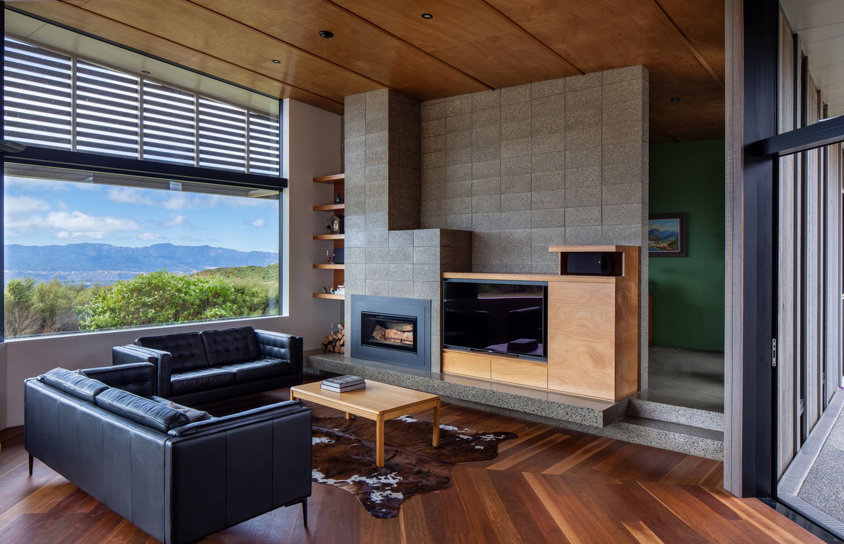 The living area incorporates Parsonson Architects' signature bespoke cabinetry. A pops of green wall indicates the study in behind.