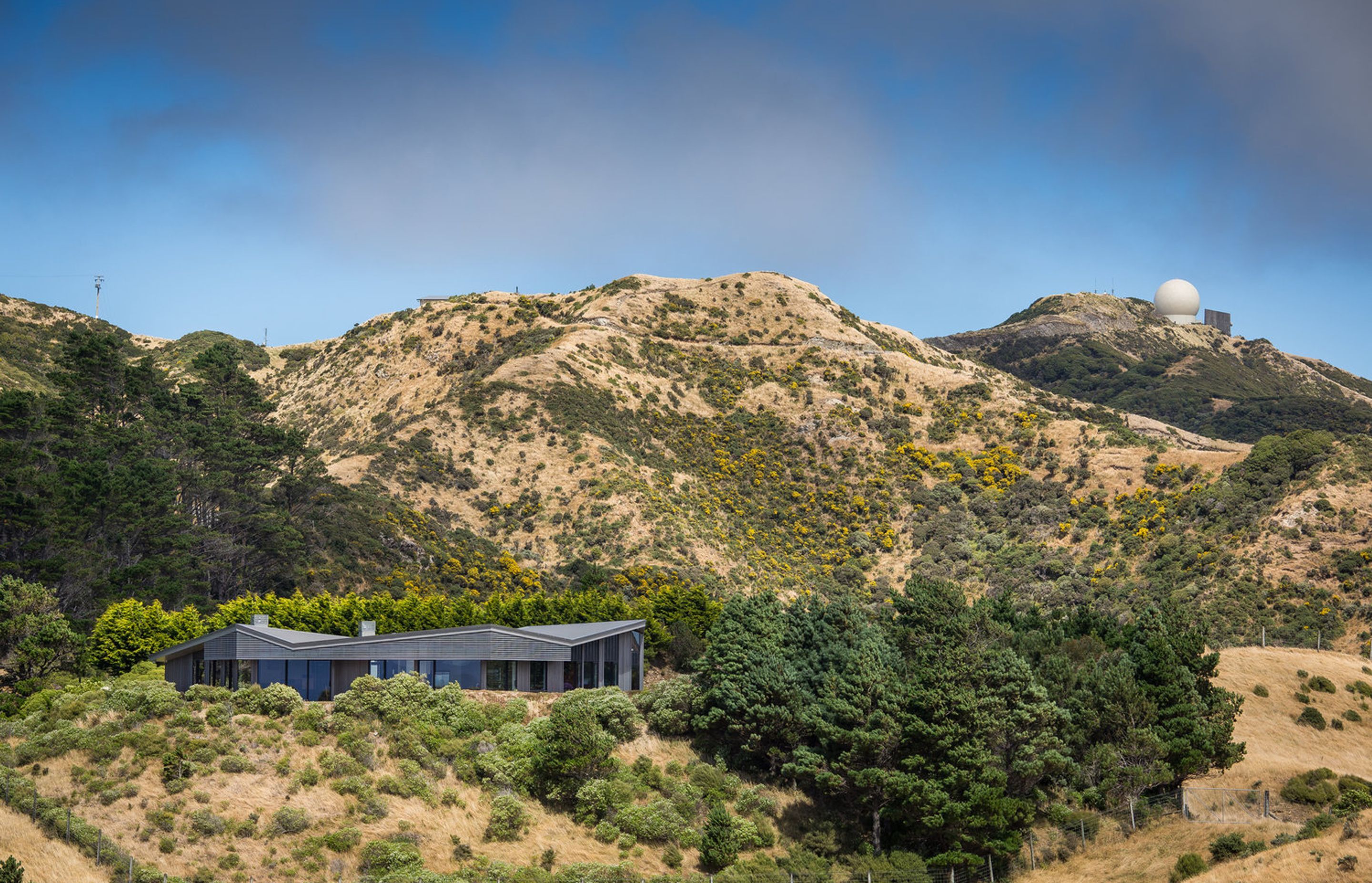 This contemporary rural house tops off a hill excavated a long time ago, completing its form. Its low-slung form is "slightly undulating – like the rolls of the neighbouring hills."