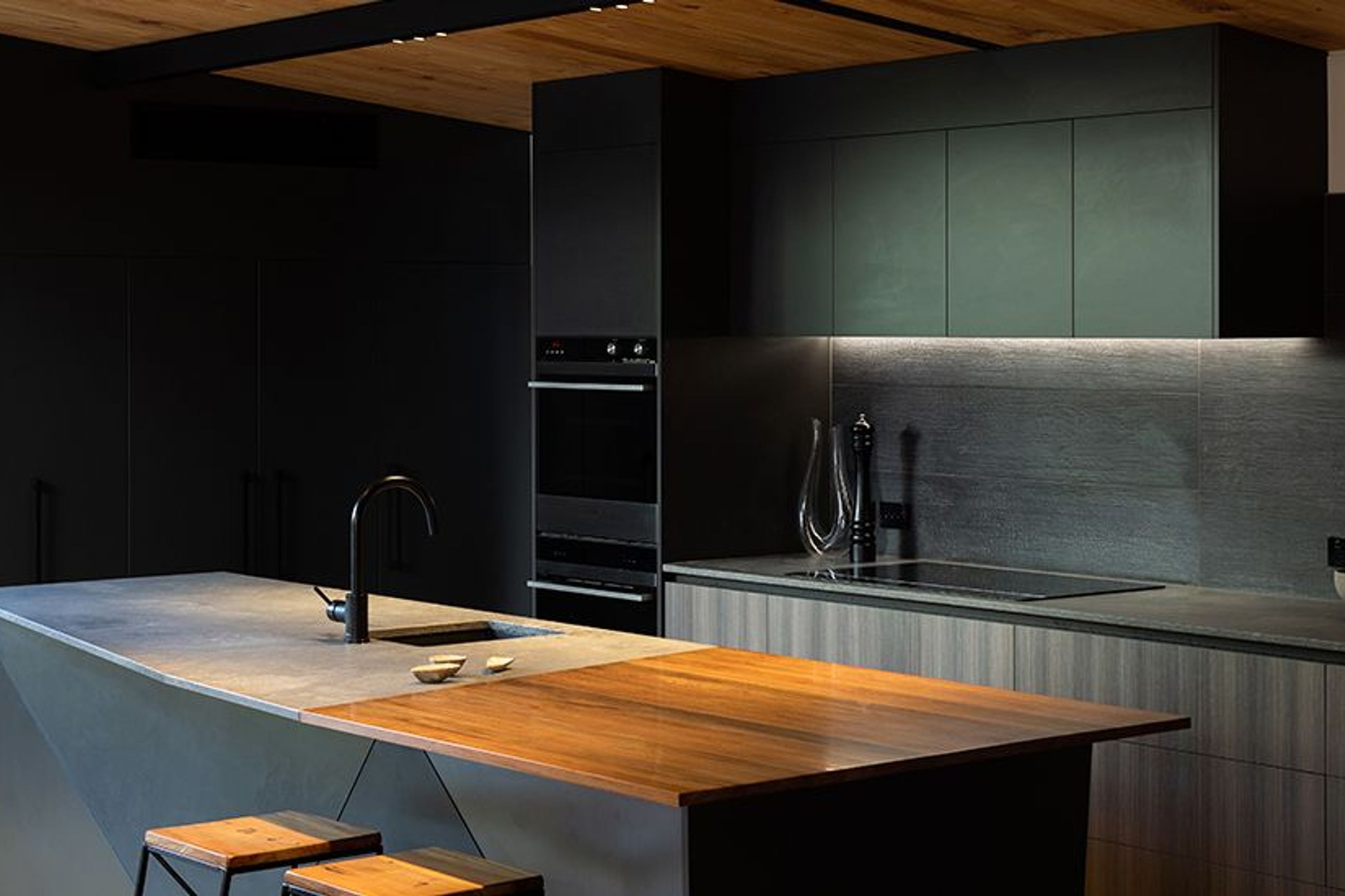 This stunning kitchen has a swamp rimu slab nestled into a rugged concrete Caesarstone benchtop by Laminex  Custom cabinetry by Prime Panels in dark grey complete the look.