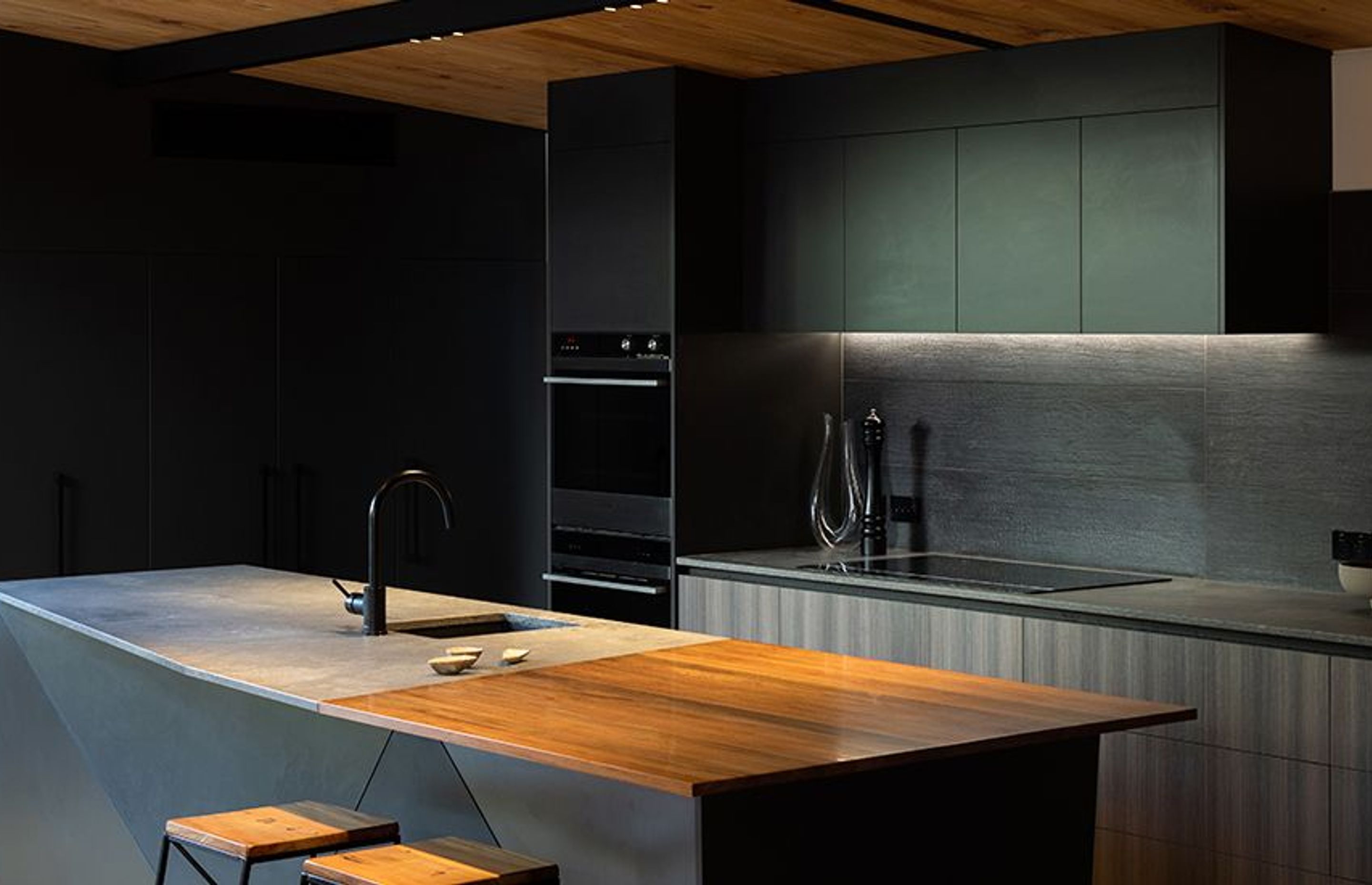 This stunning kitchen has a swamp rimu slab nestled into a rugged concrete Caesarstone benchtop by Laminex Custom cabinetry by Prime Panels in dark grey complete the look.