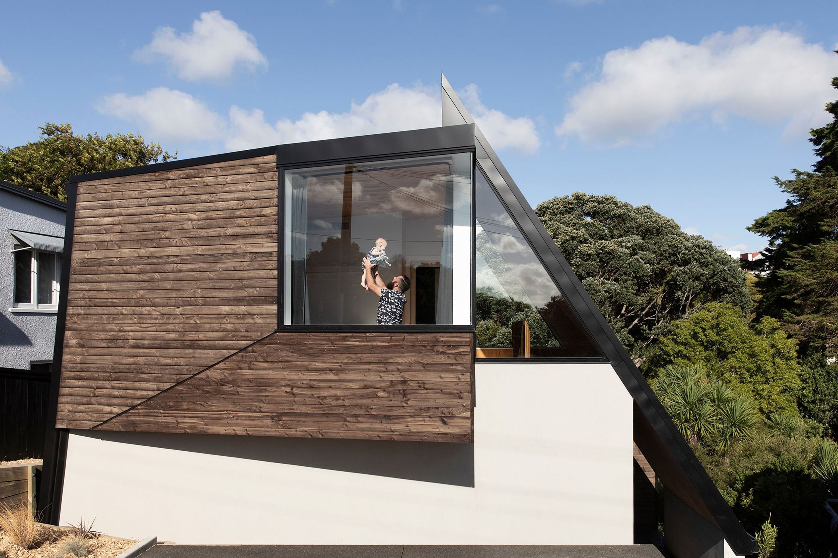 Designer Craig Wilson with his son in the master bedroom. The faceted timber cladding is treated with iron vitriol by Abodo.