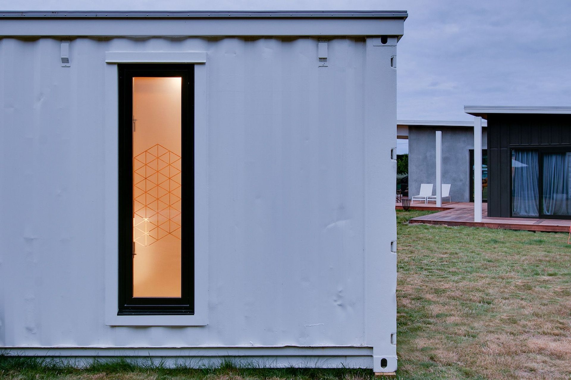 A close-up view of the end of the shipping container, with a glimpse of the house next door.