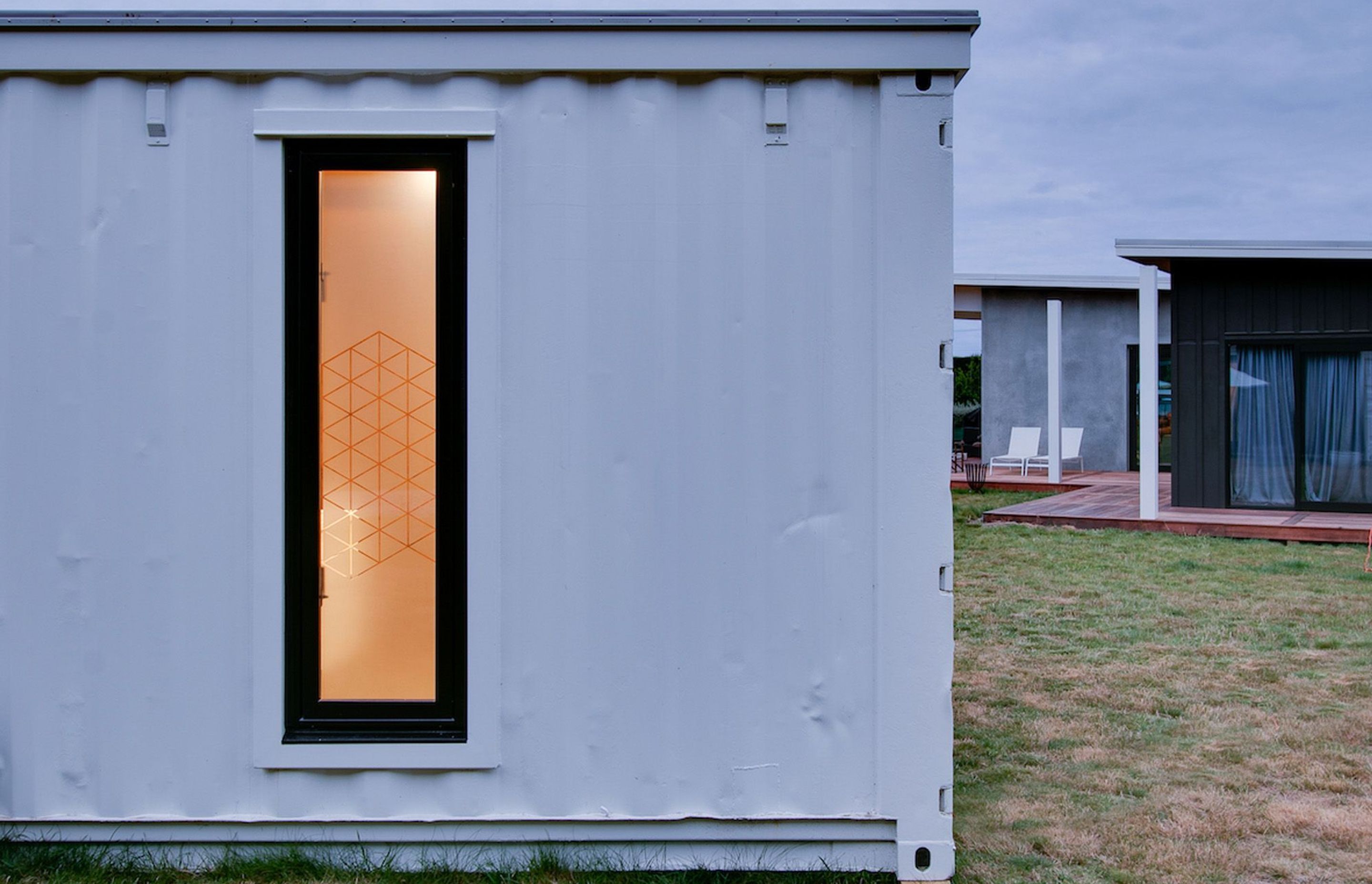 A close-up view of the end of the shipping container, with a glimpse of the house next door.