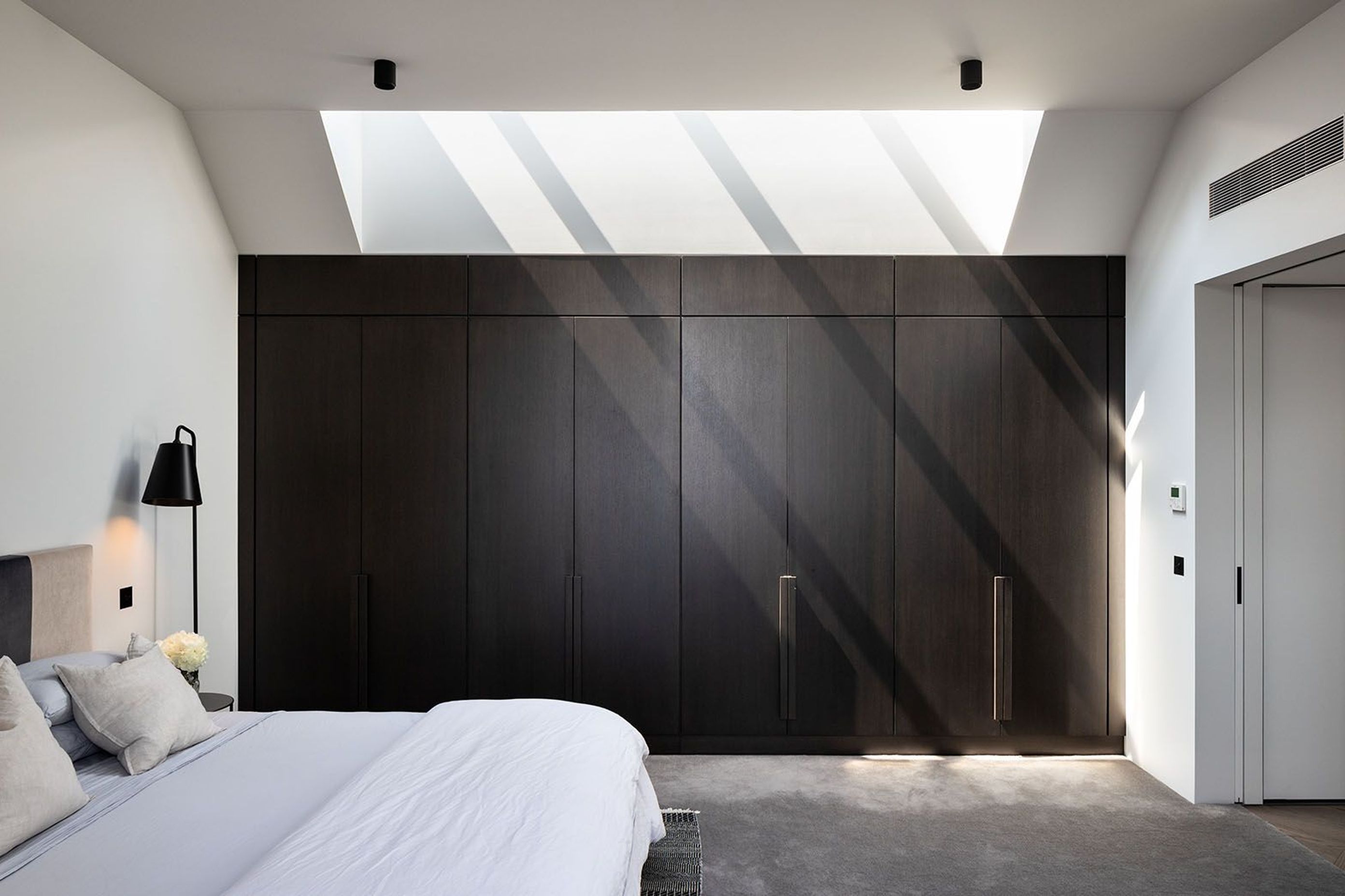 The master bedroom offers a continuation of the dark palette but creates a softness of light and texture.