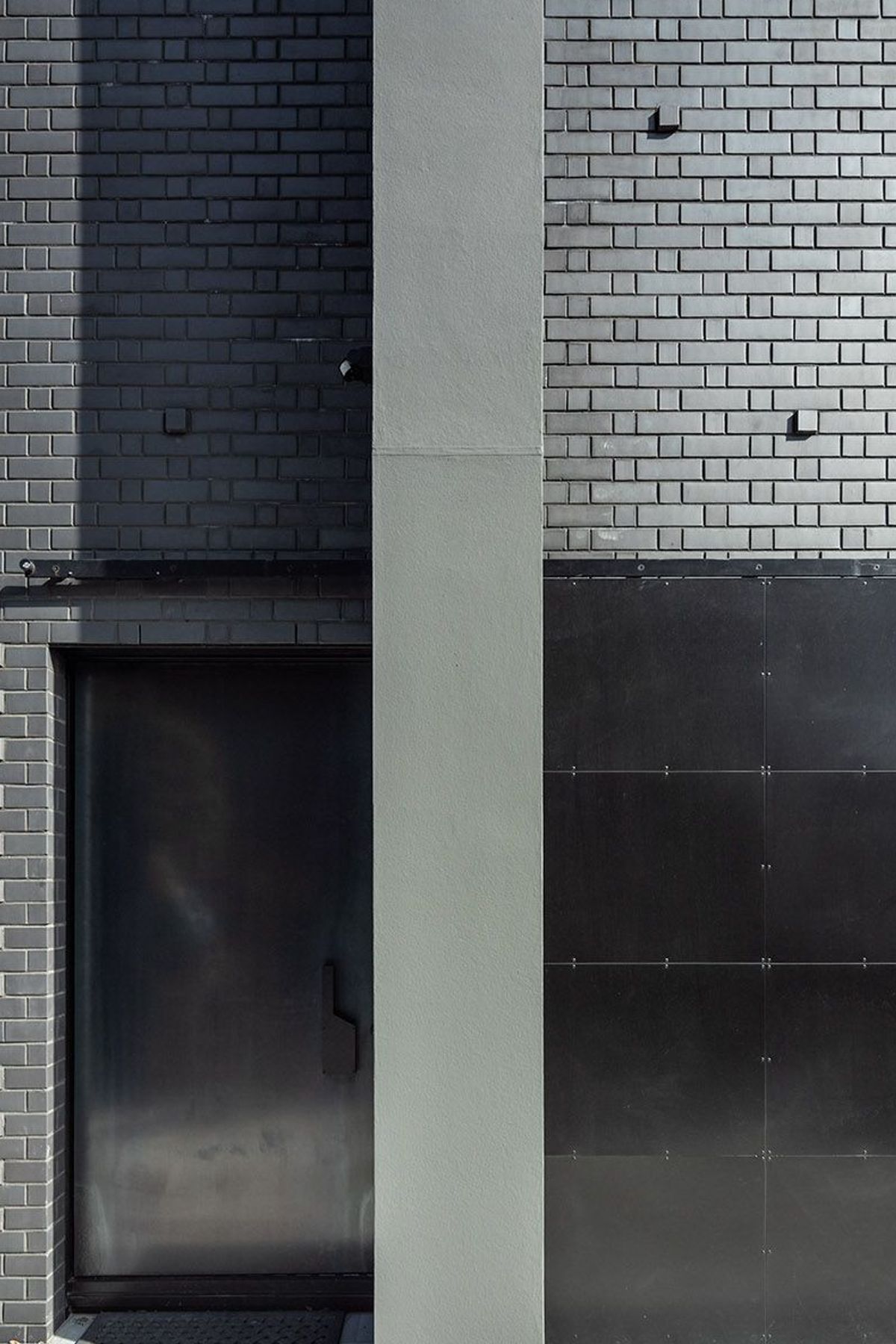 Here, the hot-rolled steel entry door is tucked away behind a bespoke hot rolled steel barn-style door; an entrance that gives little away.
