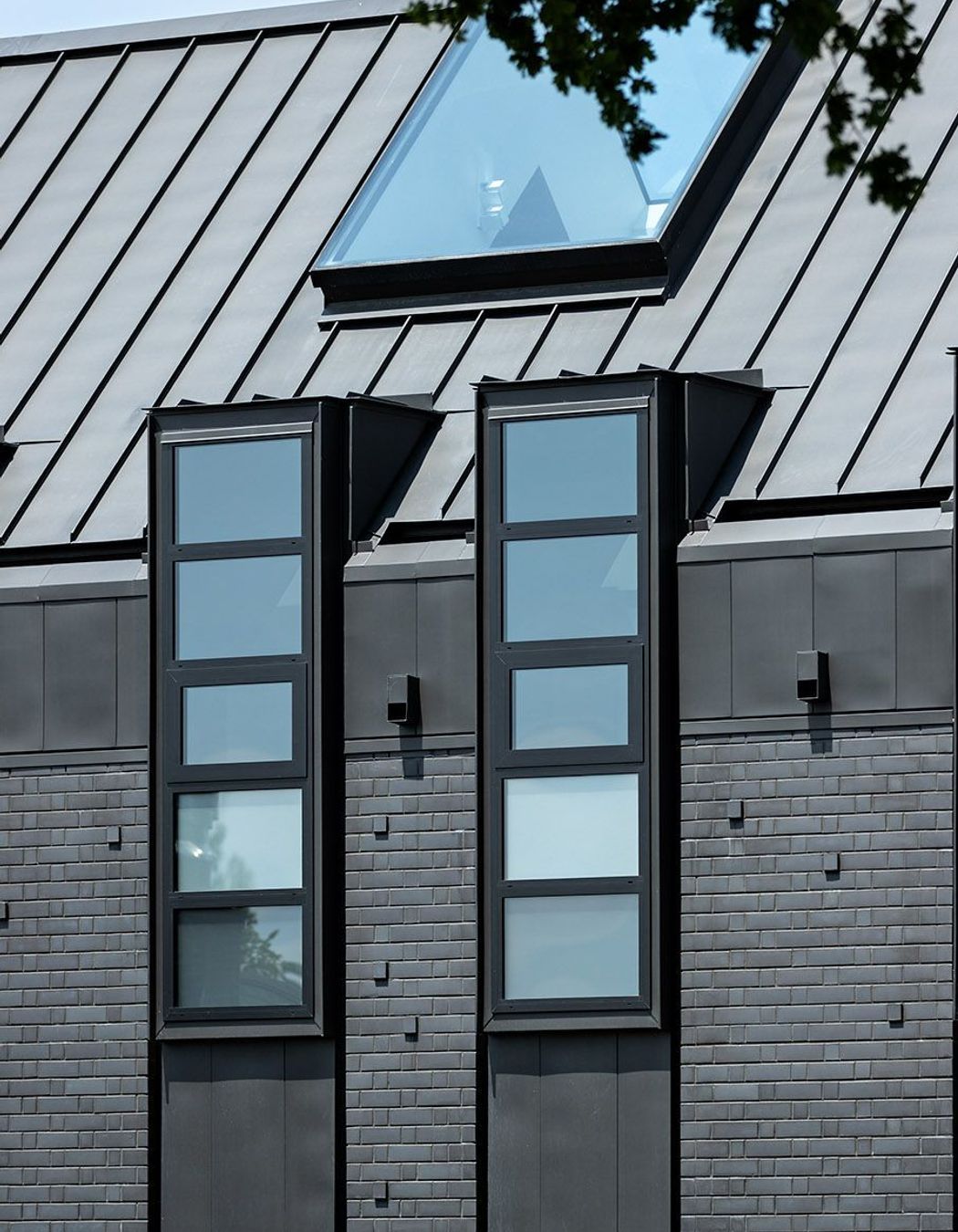 The northern facade is punctuated by a series of steel-lined dormer windows framing glimpses of borrowed landscapes from the neighbouring properties.