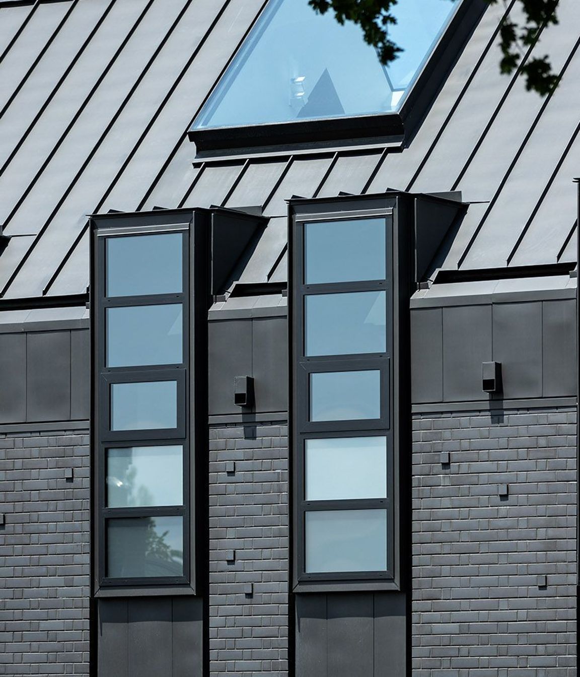 The northern facade is punctuated by a series of steel-lined dormer windows framing glimpses of borrowed landscapes from the neighbouring properties.