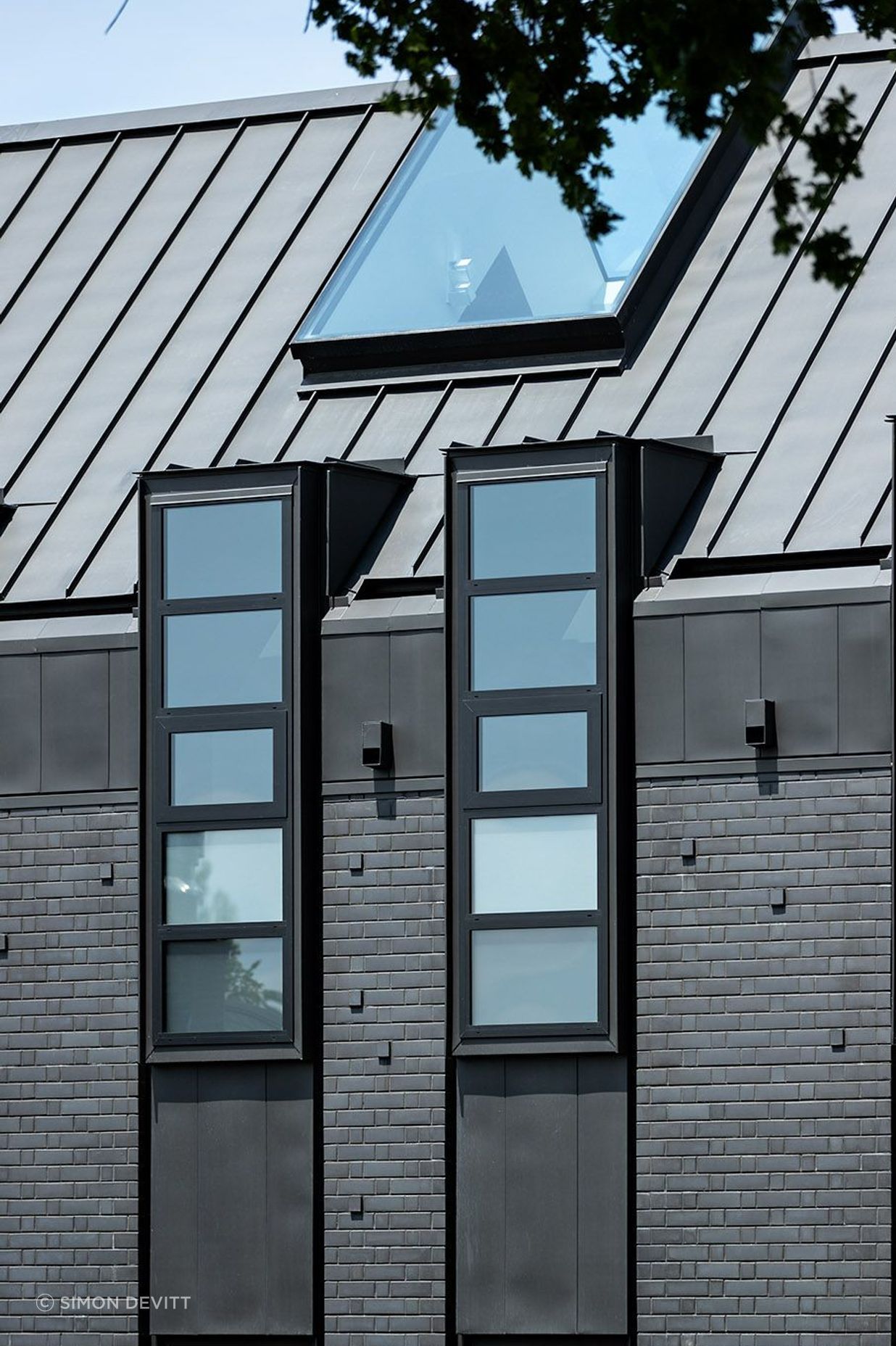 The northern facade is punctuated by a series of steel-lined dormer windows framing glimpses of borrowed landscapes from the neighbouring properties.