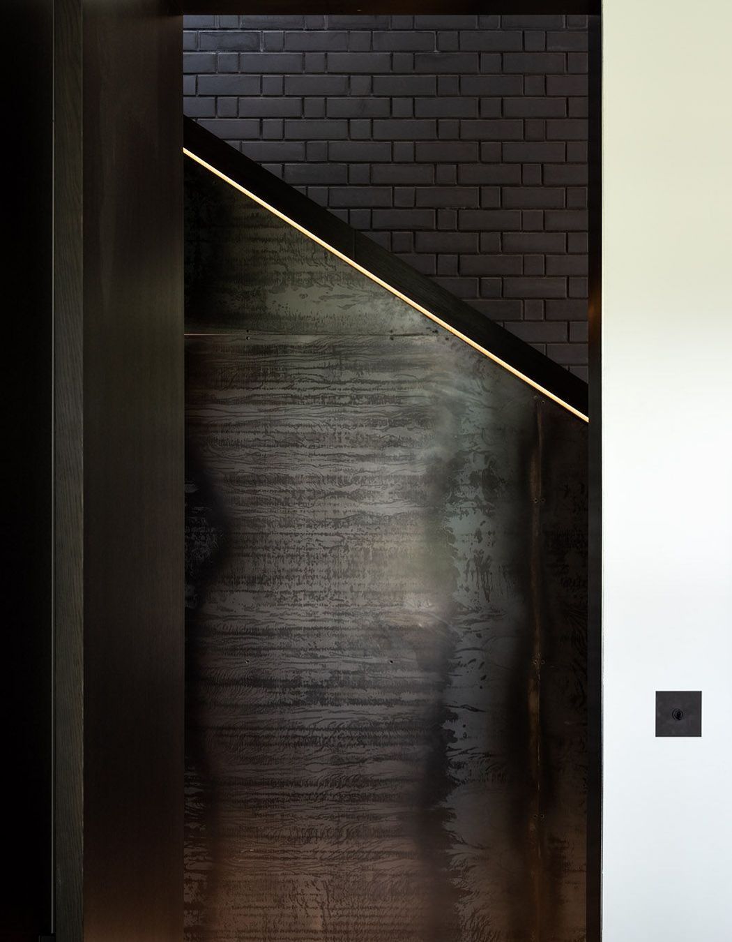 Here, a sculptured, boxed timber handrail whose detailing is illuminated by recessed LED strip lights. becomes a juxtaposition to brick and steel.