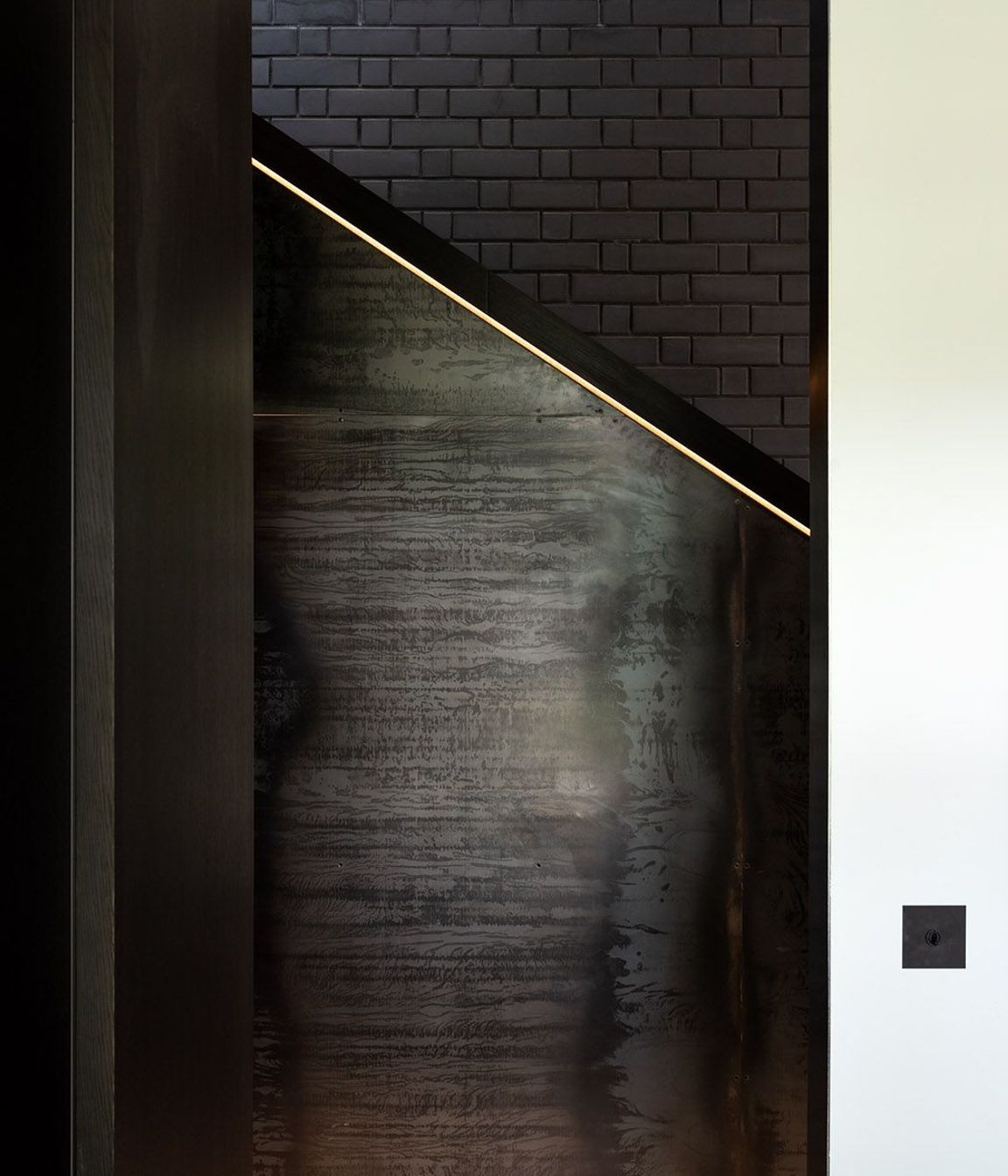 Here, a sculptured, boxed timber handrail whose detailing is illuminated by recessed LED strip lights. becomes a juxtaposition to brick and steel.