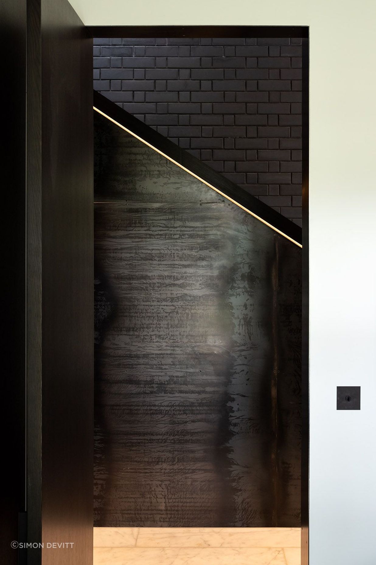 Here, a sculptured, boxed timber handrail whose detailing is illuminated by recessed LED strip lights. becomes a juxtaposition to brick and steel.