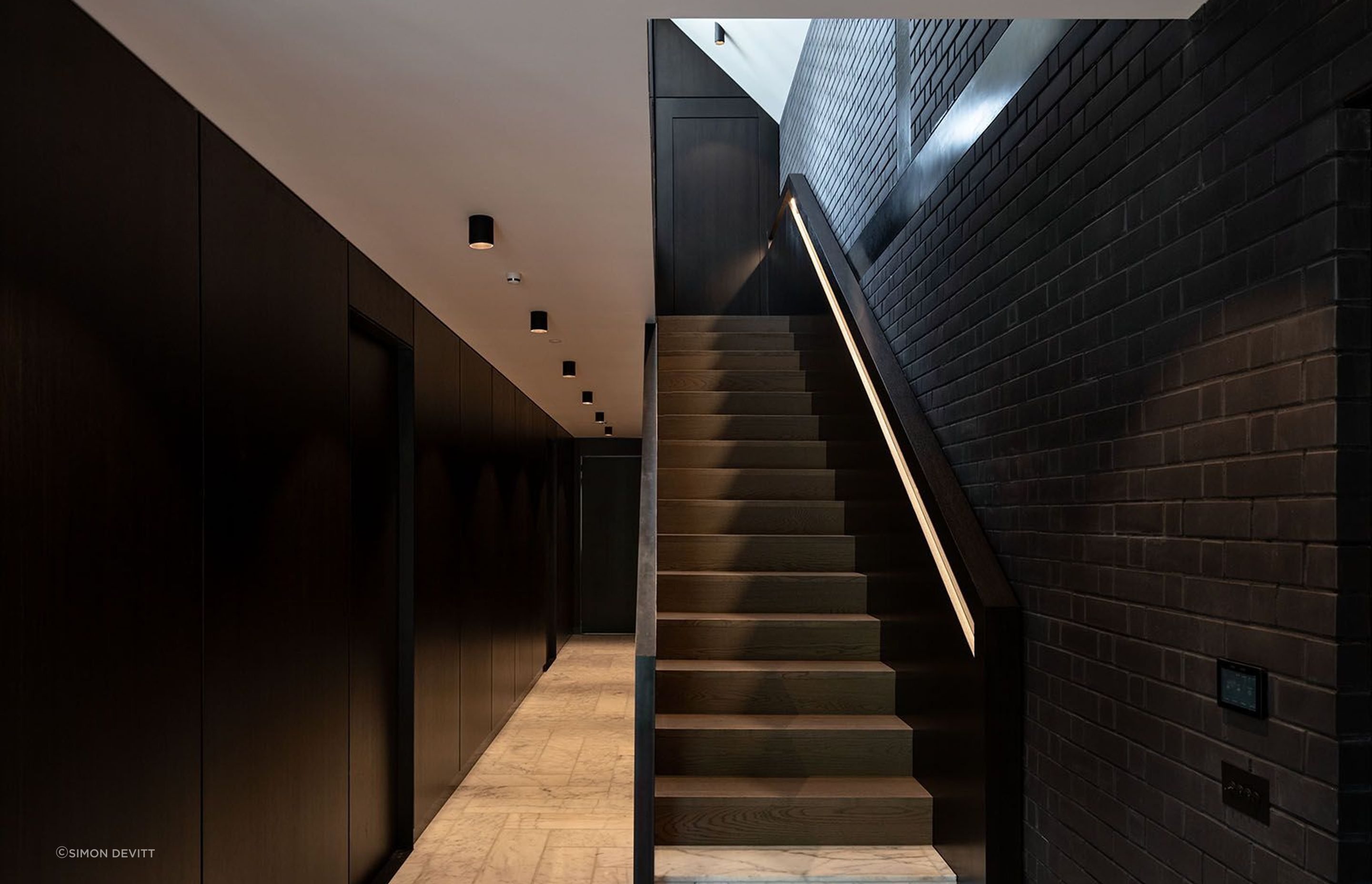 This corridor acts as the spine of the home - a spacious area that gives little away aside from an offering of texture and juxtaposition of colour.
