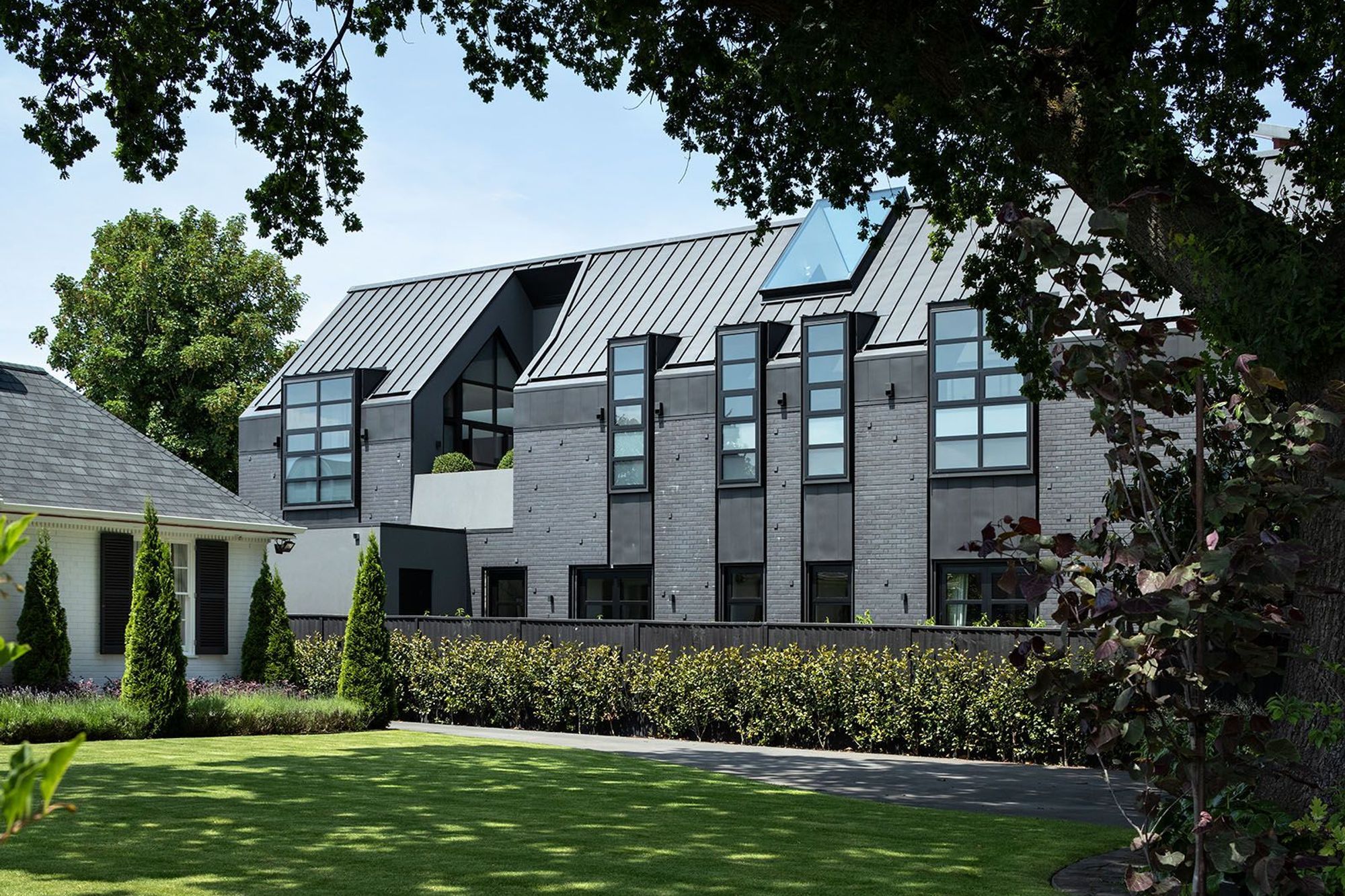 The Flemish bond brick façade combined with dormer windows and a patio carved out of the gabled form create a stunning and imposing elevation.