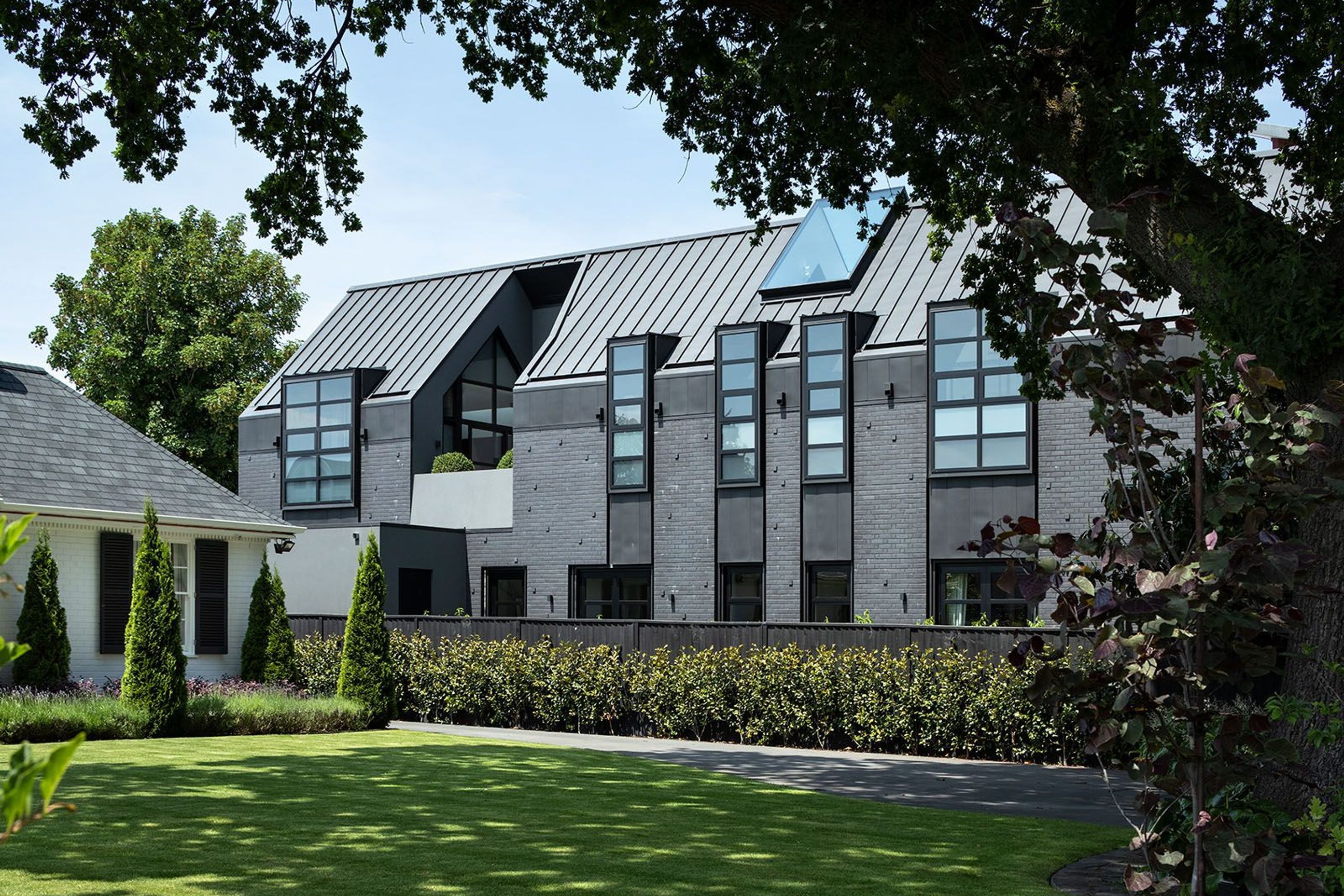 The Flemish bond brick façade combined with dormer windows and a patio carved out of the gabled form create a stunning and imposing elevation.