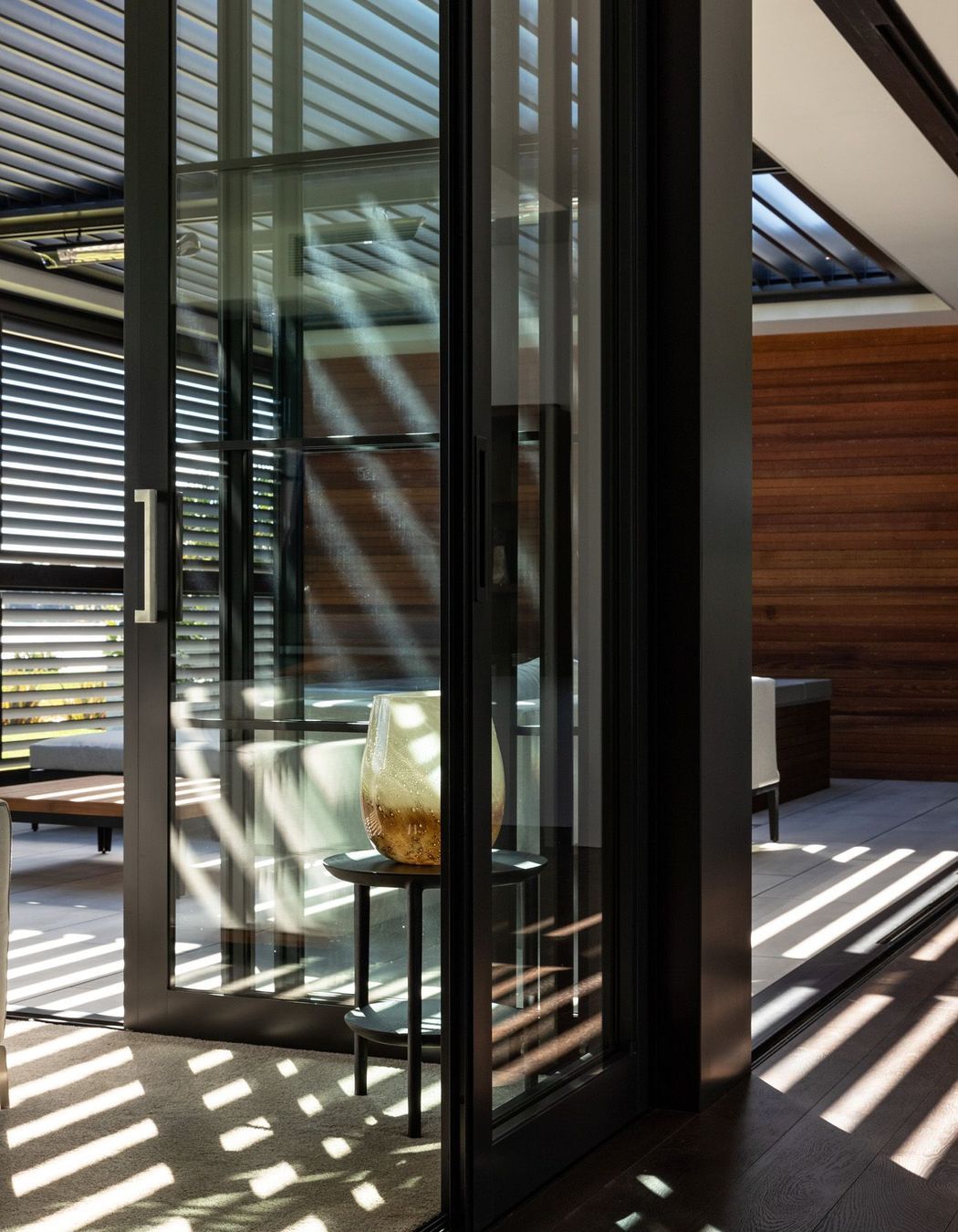 Louvres cast light and shadow into the outdoor room, which opens up on two sides.