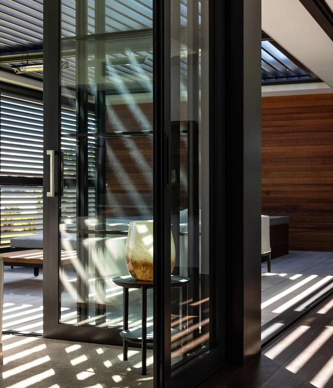 Louvres cast light and shadow into the outdoor room, which opens up on two sides.