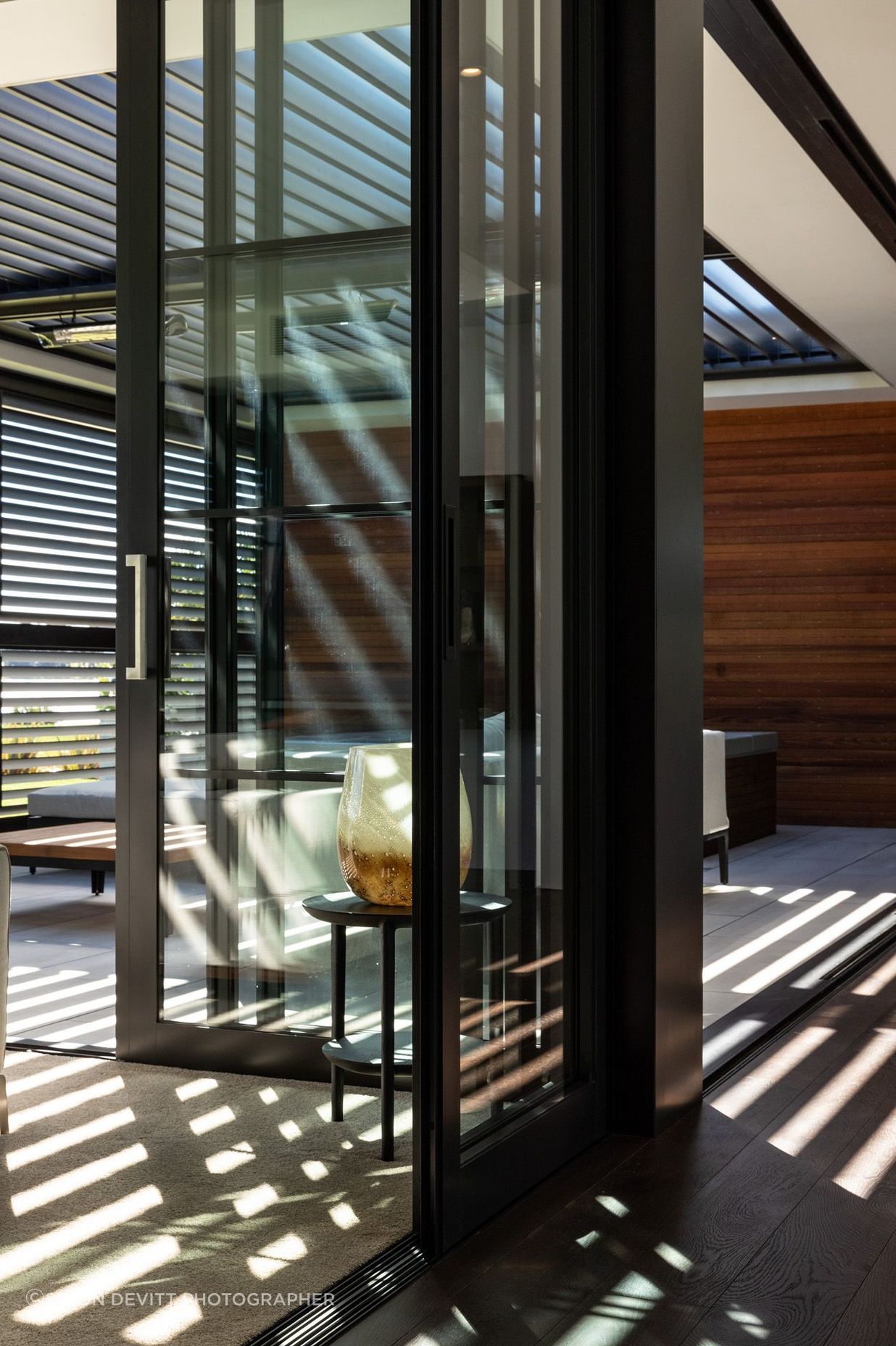 Louvres cast light and shadow into the outdoor room, which opens up on two sides.