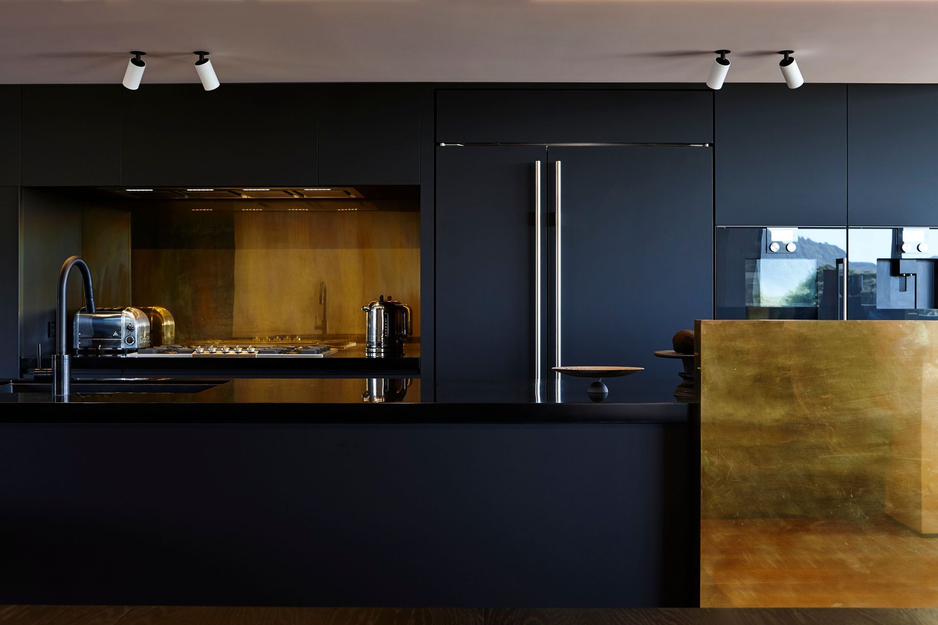 Copper elements accent the otherwise monochromatic kitchen, harnessing light and casting flashes of fire around the living room.