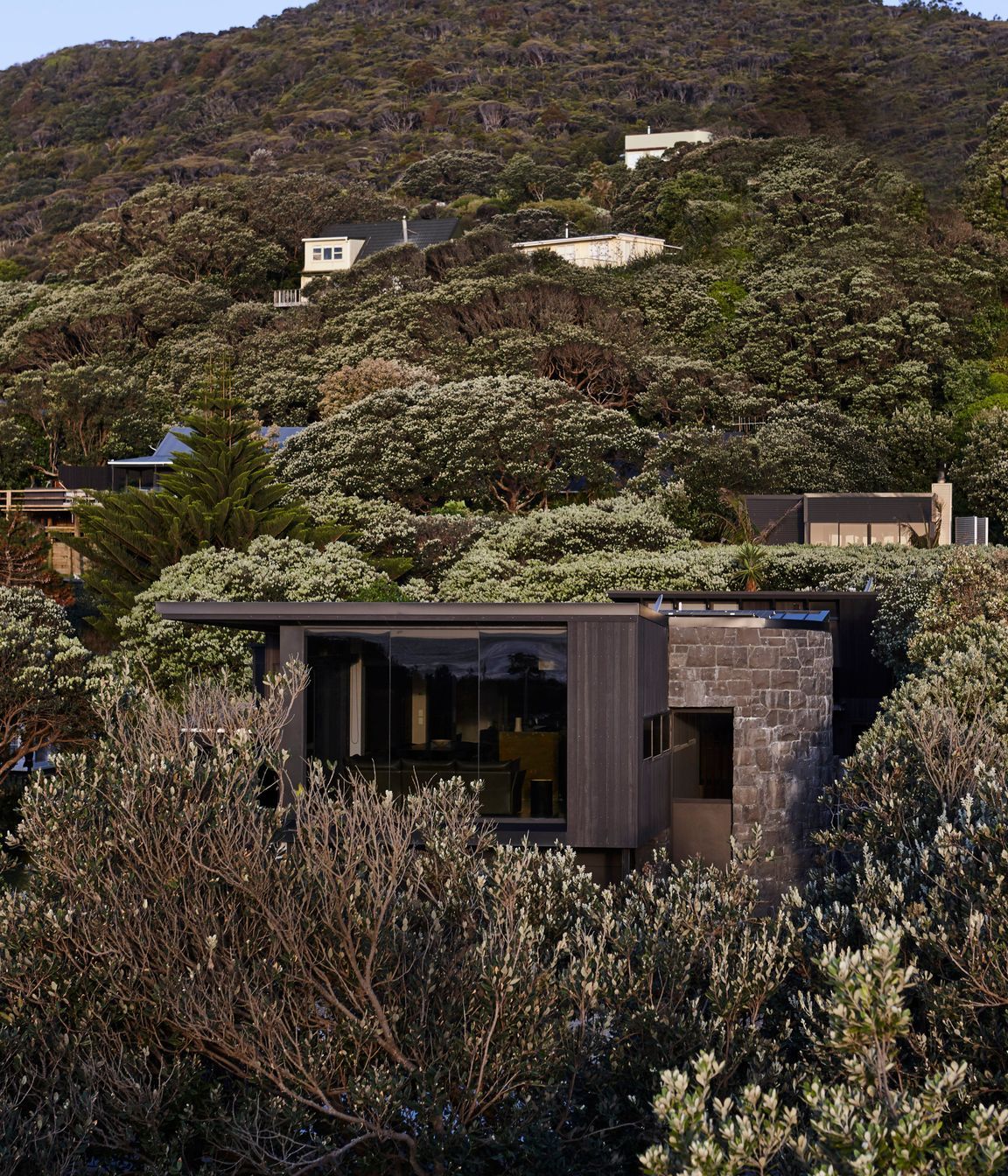 Sympathetic to its surroundings, Piha House nestles into its beachside locale.