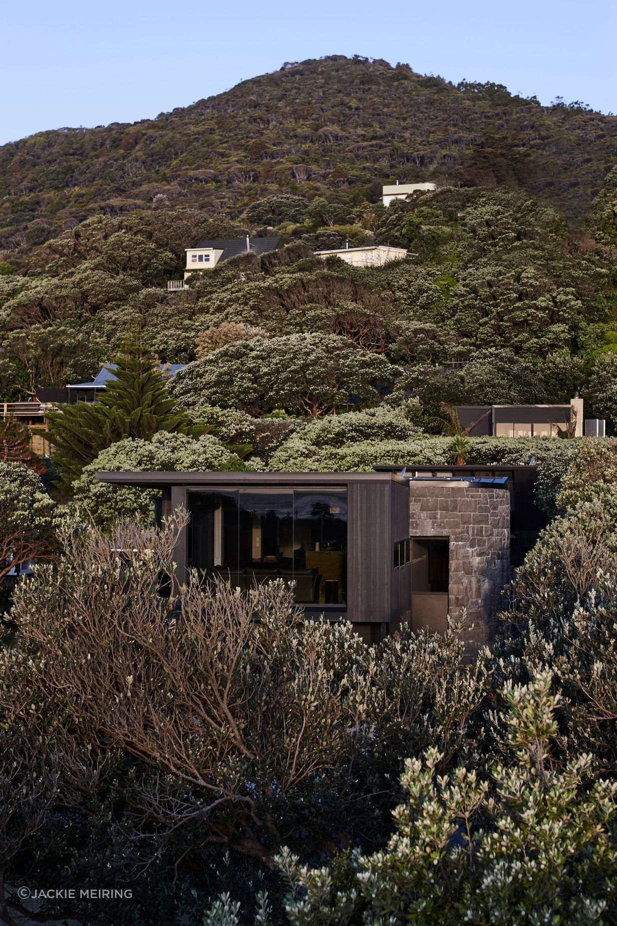 Sympathetic to its surroundings, Piha House nestles into its beachside locale.