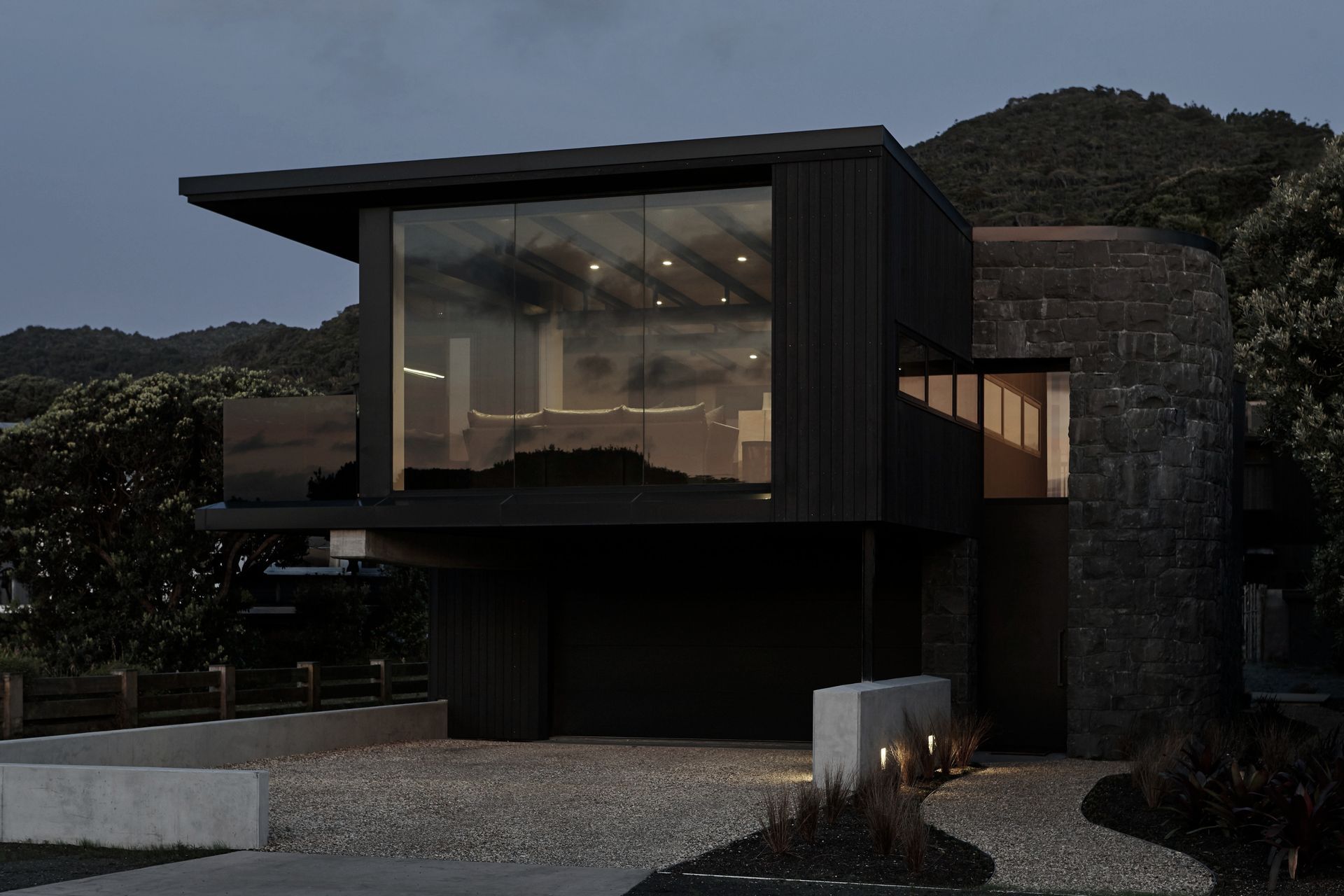 The pared back material palette features black-stained cedar, tinted low-emissivity glass and a basalt-clad curved entry element.