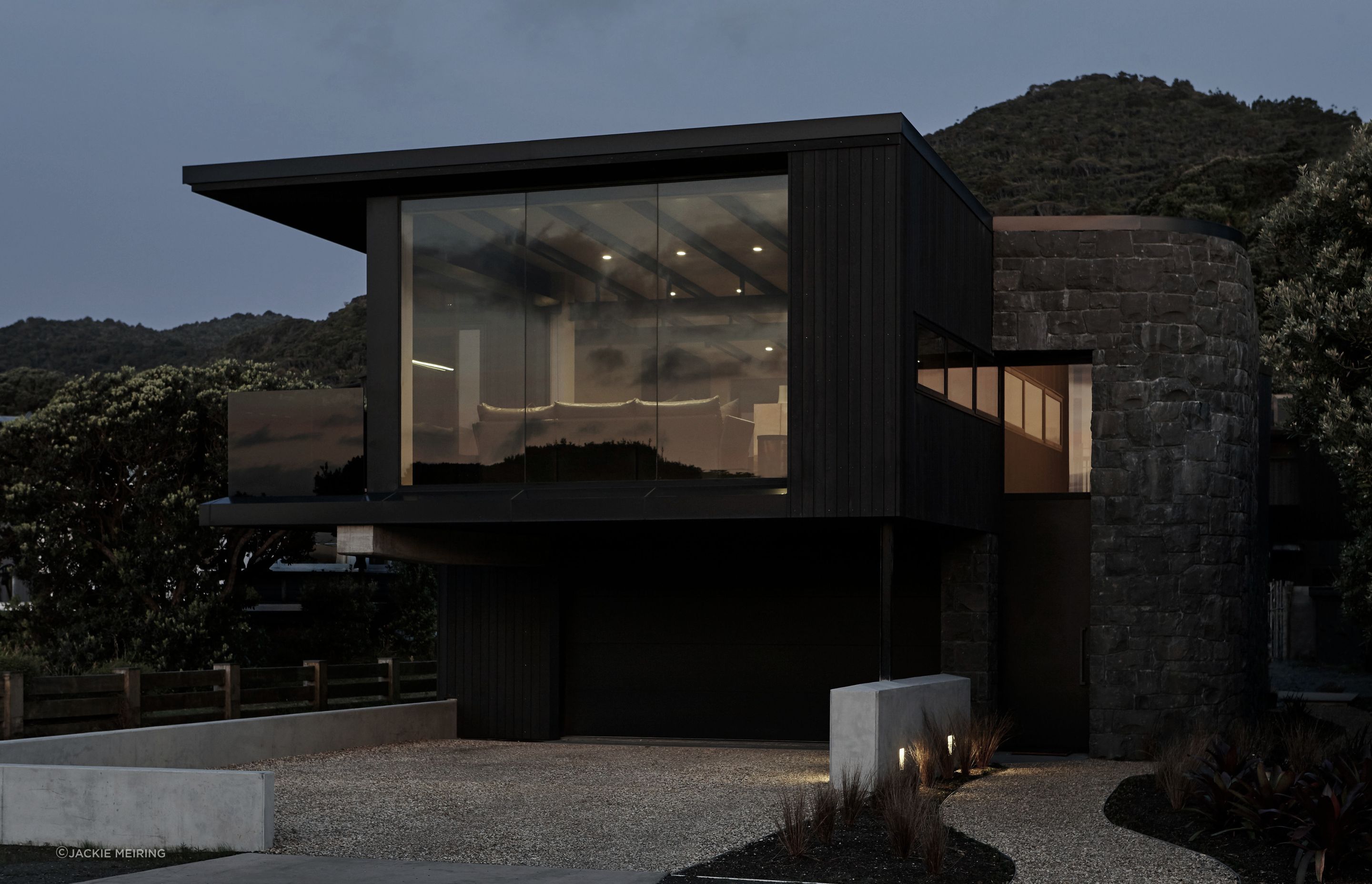 The pared back material palette features black-stained cedar, tinted low-emissivity glass and a basalt-clad curved entry element.